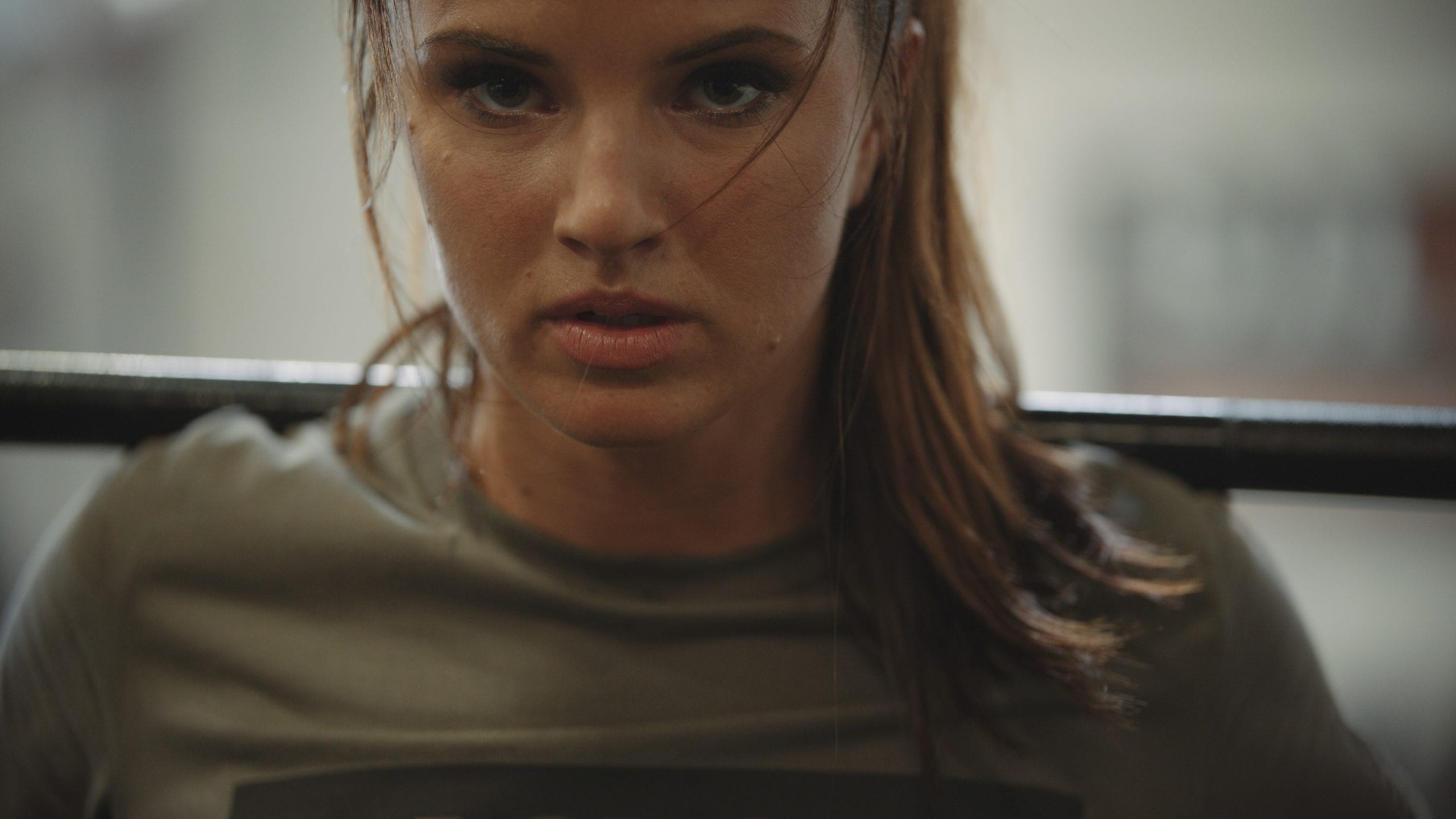 Closeup of woman wearing a gray t shirt lifting weight