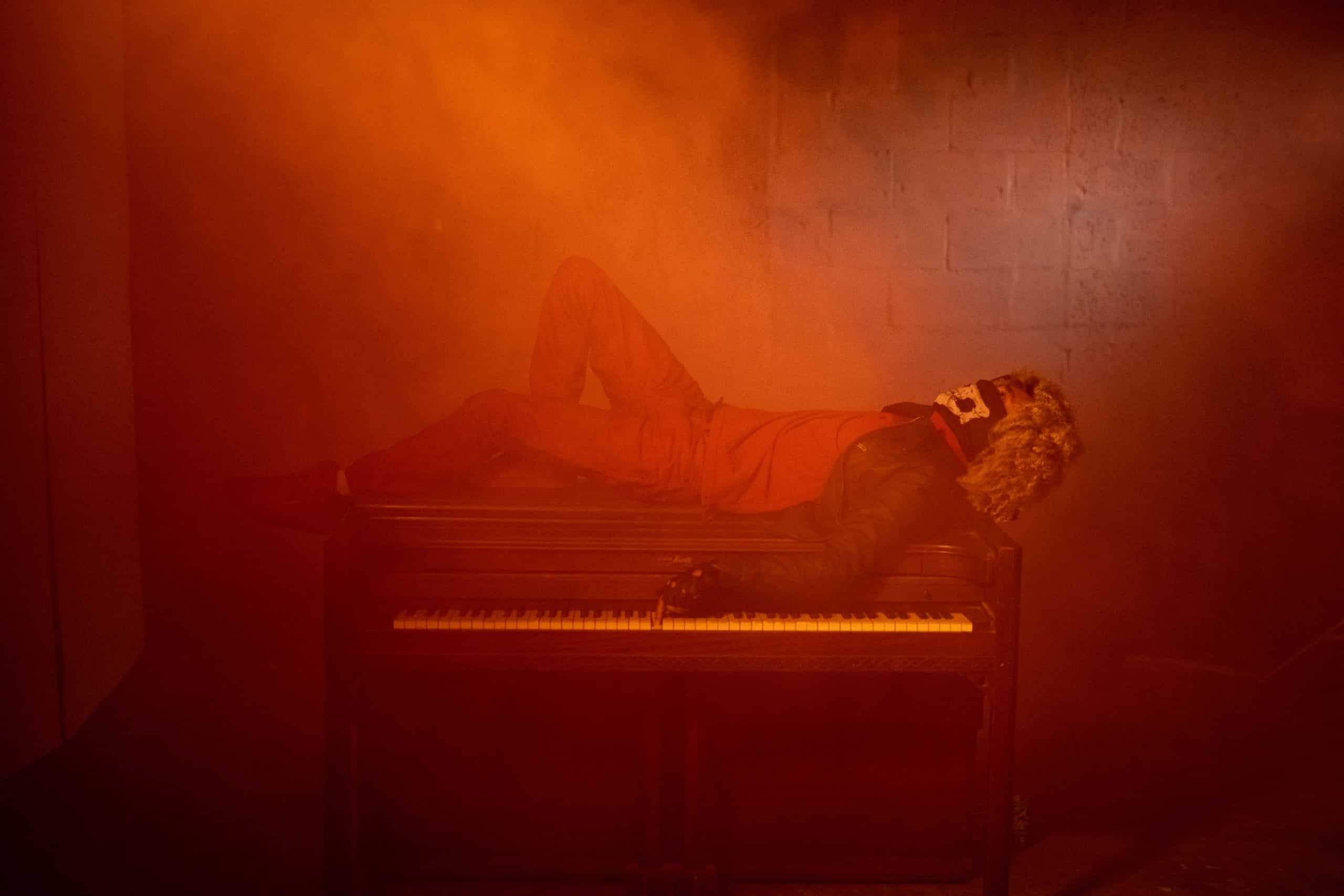 The importance of web design and color theory Side profile of someone laying on a piano with a skeletal mask on with a finger on the keyboard