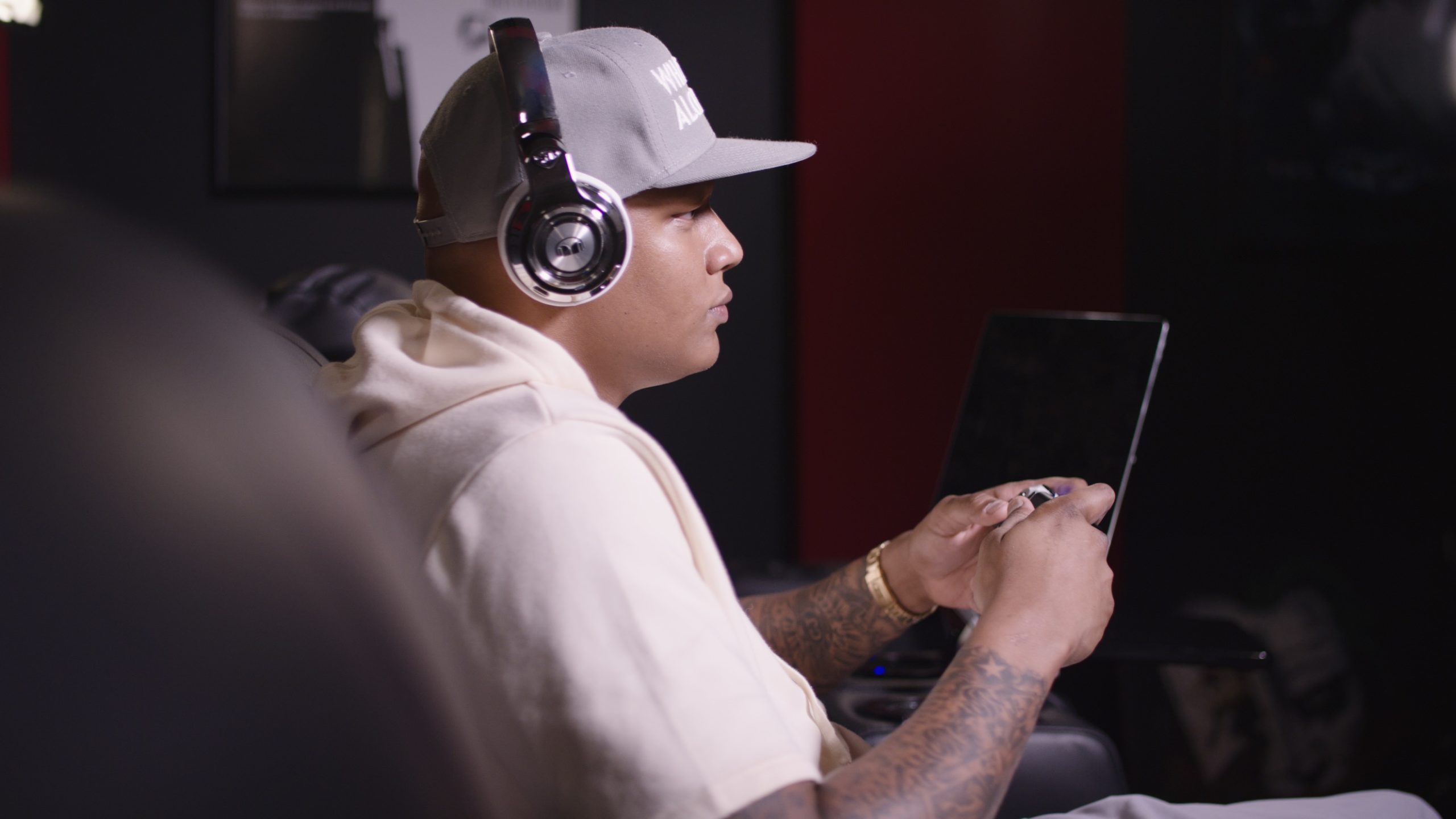 Monster Music Charlie Villanueva Side profile of man wearing headphones and gray cap using a video game controller