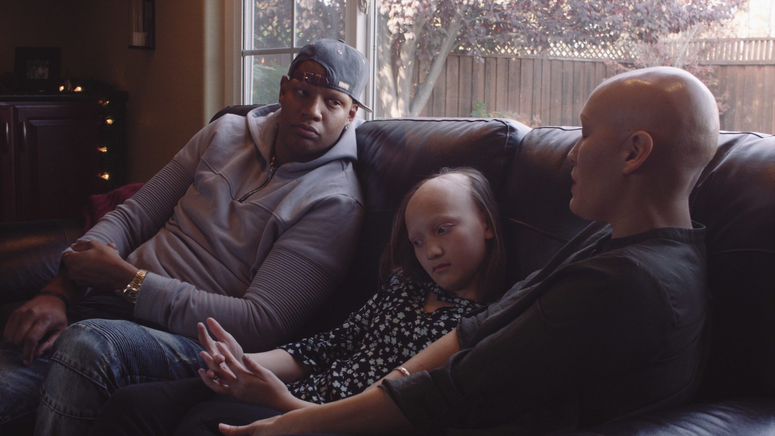 Video Documentary on Charlie Villanueva What is alopecia Man wearing a grey sweatshirt sitting on a couch with girl and woman with the condition