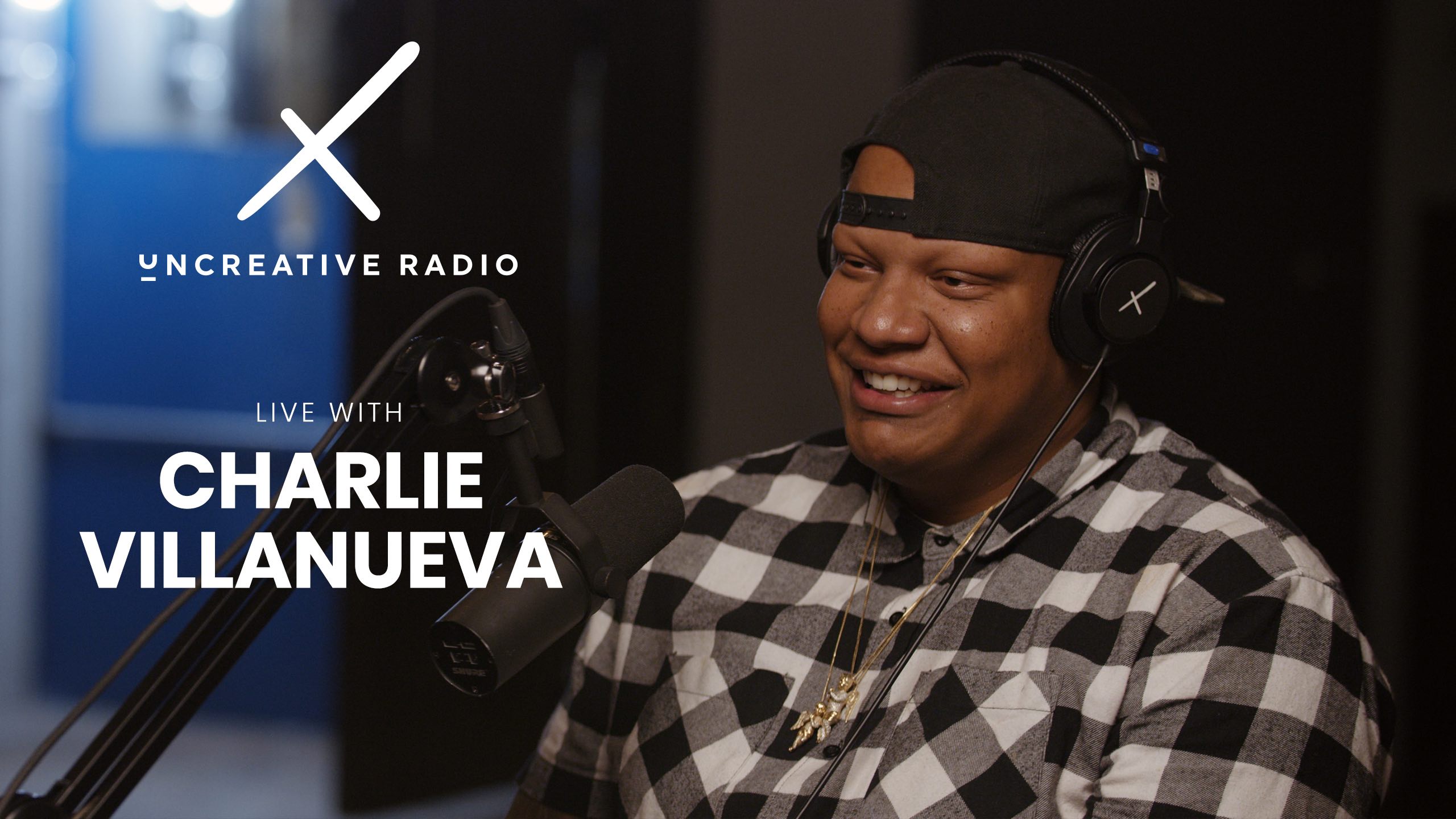 White Uncreative Radio Live With Charlie Villanueva logo with him wearing a black cap backwards and a black and white checkered shirt by a microphone and smiling