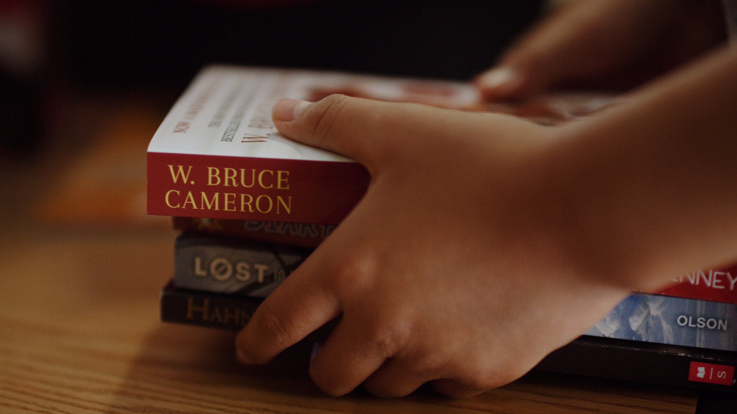 Hollywood Community Housing company profile Closeup of child hands holding a stack of books on a wooden table