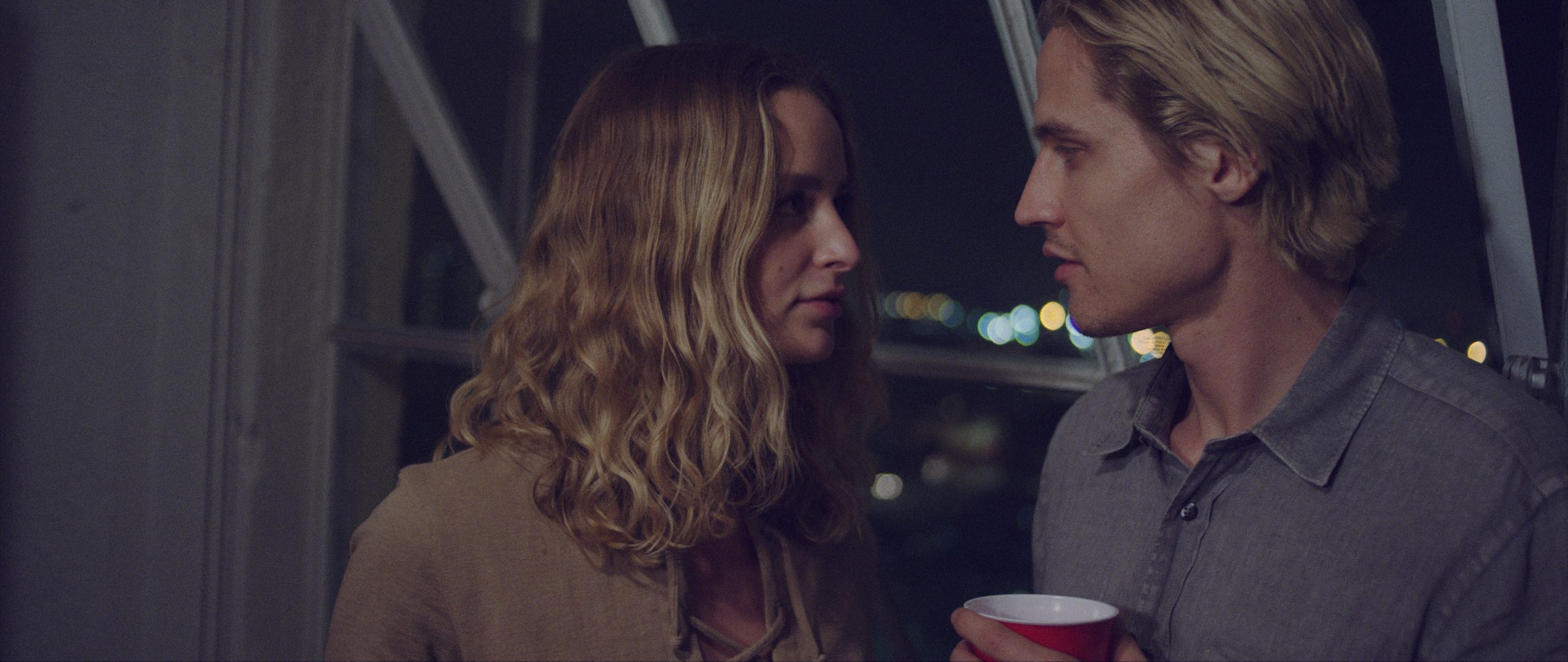 Jellyfish Short Film Produced by C&I Studios Man and woman with blond hair looking at each other by the window with man holding a red cup