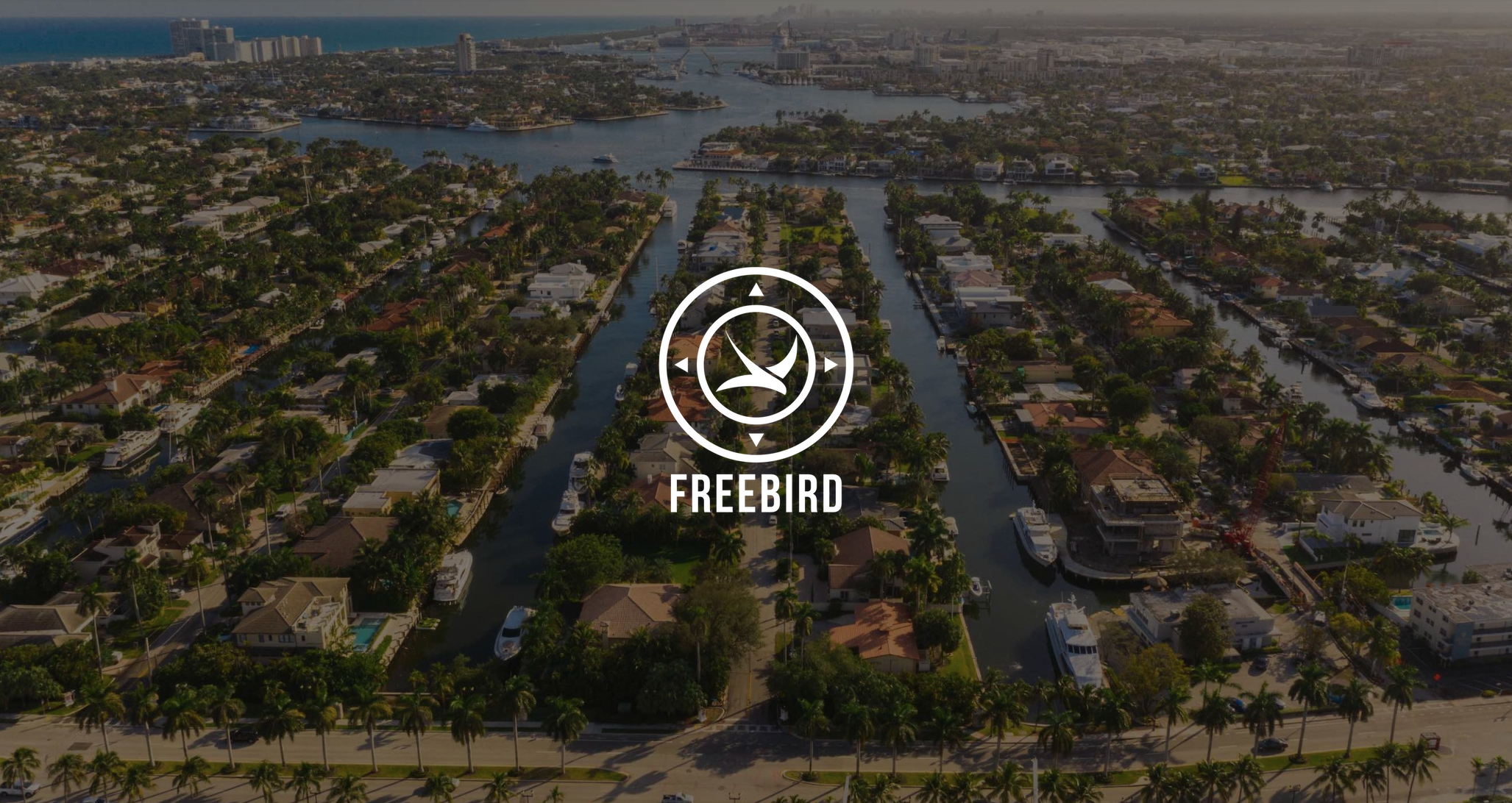 IU C&I Studios Page White Freebird Real Estate Fort Lauderdale Logo with background aerial of boats in canals in the city