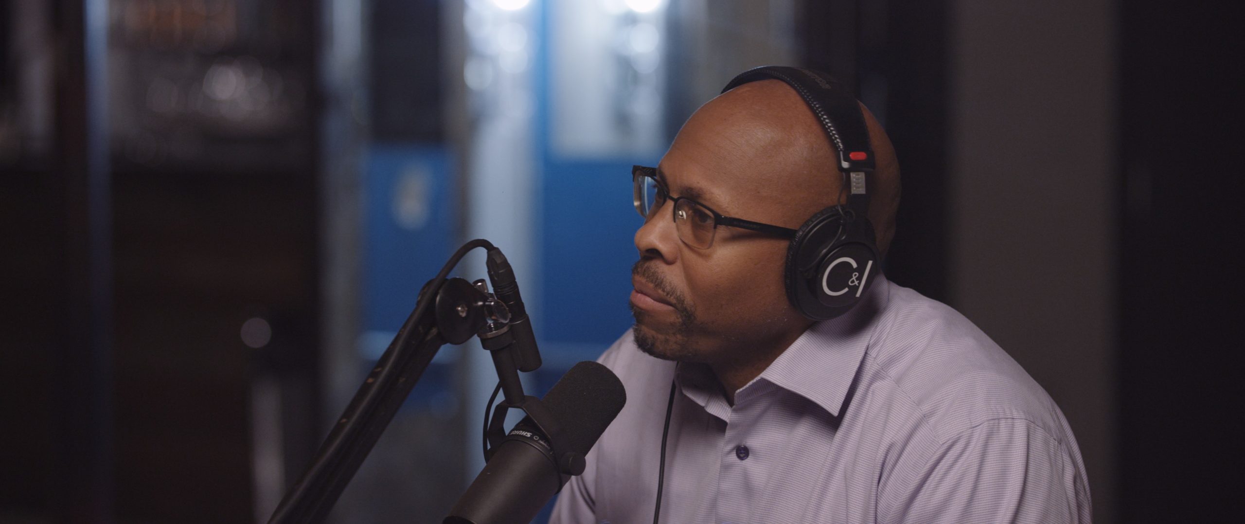 Uncreative Radio with Rob Richardson side profile with a goatee sitting by a microphone wearing headphones and glasses