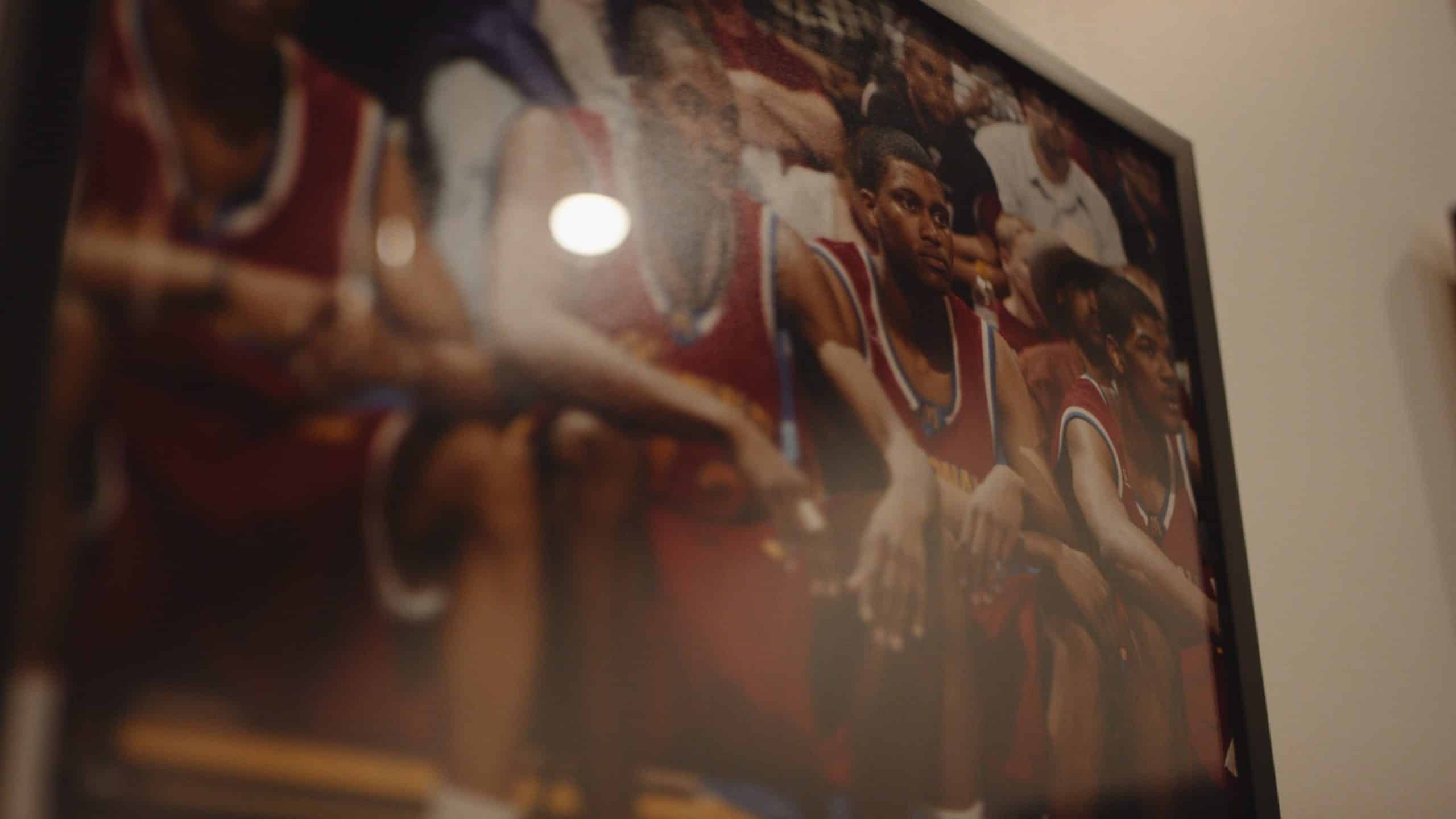 Closeup of a photo showing basketball players wearing red jerseys sitting on a bench