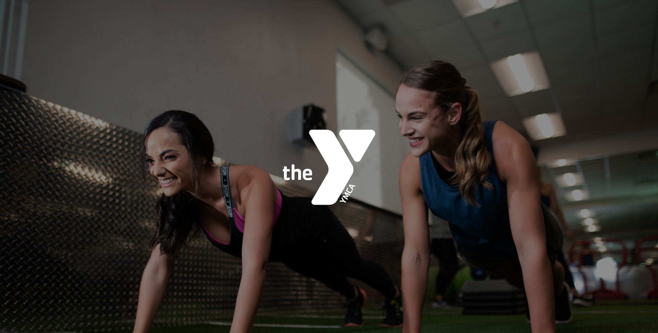 IU C&I Studios Page Graphic Design Services for YMCA of South Florida White The YMCA logo with two smiling women in plank poses in a gym