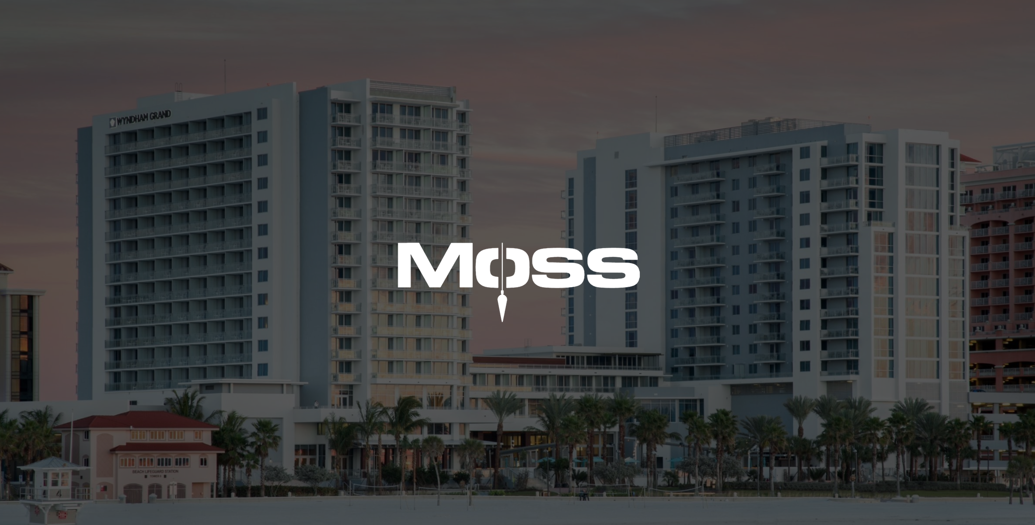White Moss logo Construction Fort Lauderdale with dimmed background of two Wyndham Grand buildings by a beach