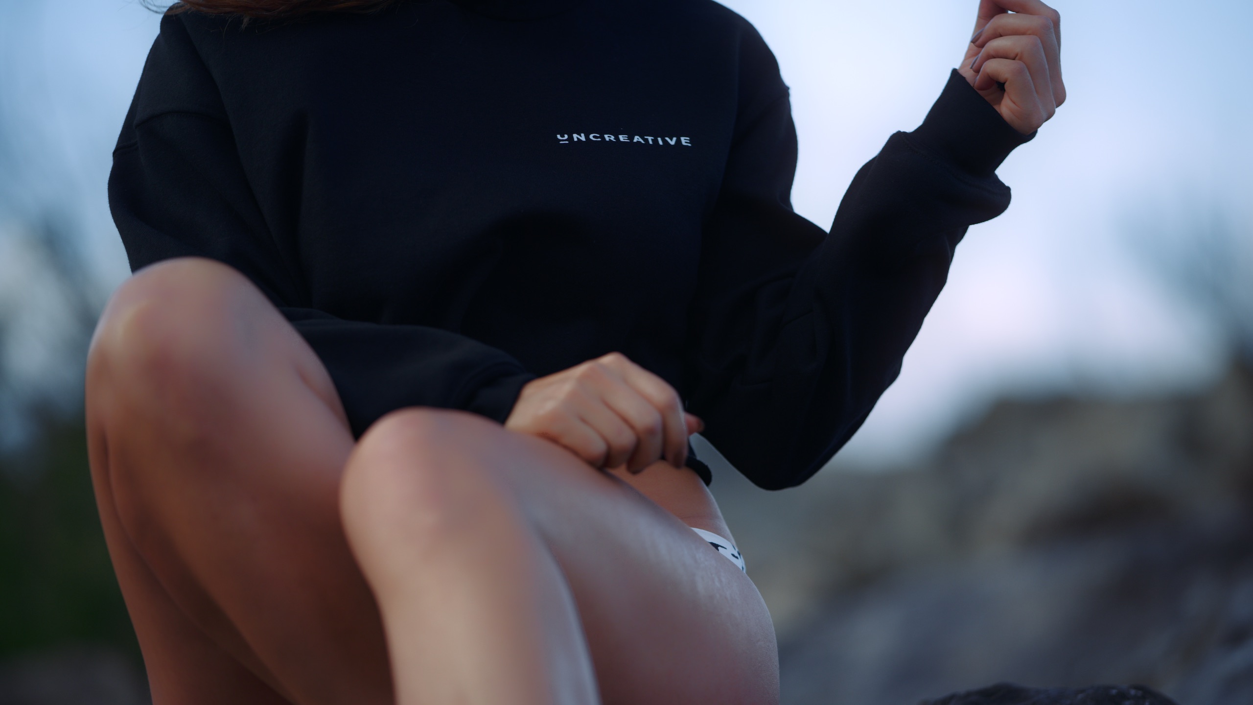Uncreative Shop Hawaii Apparel on available at the Uncreative Shop Closeup of black hoodie and lower torso of a woman posing for the camera
