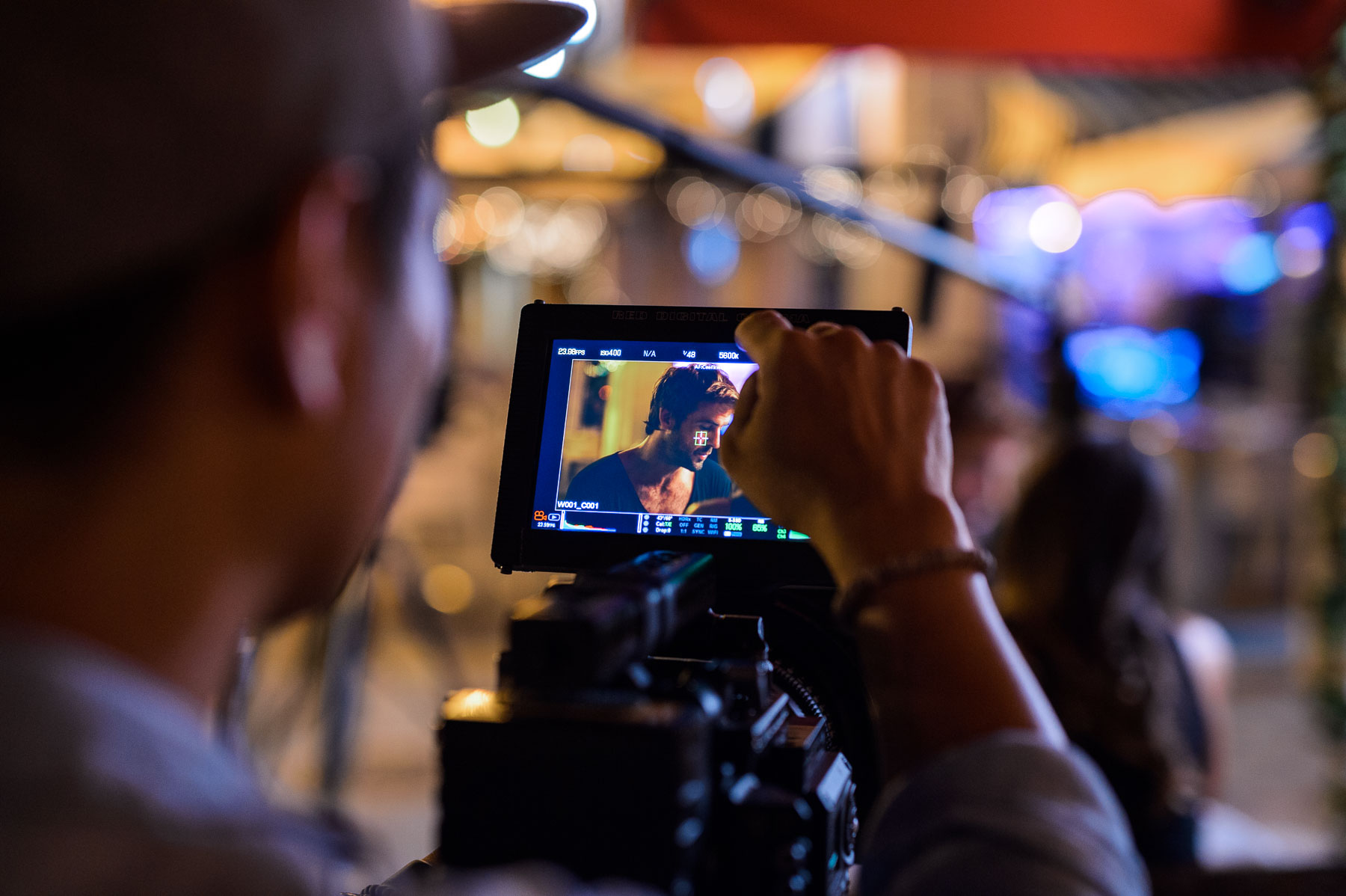 View from behind of crew member looking at movie scene on a video display