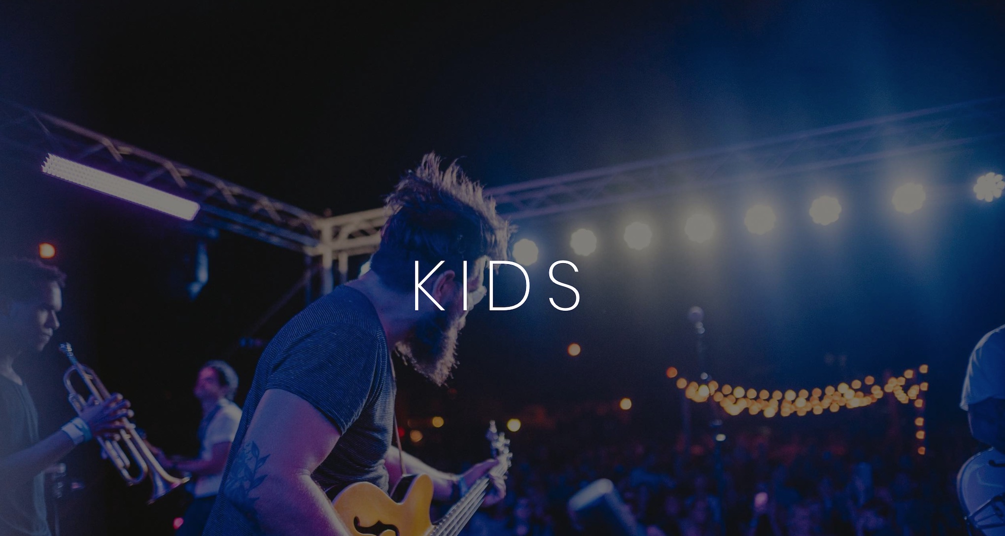 KIDS Artist Management Services White KIDS logo on background of band playing for an audience