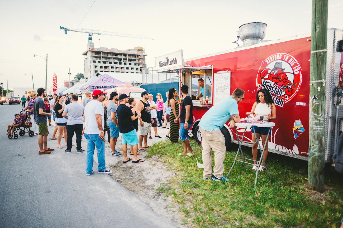 Red seafood food truck at an outside market with a crowd of people