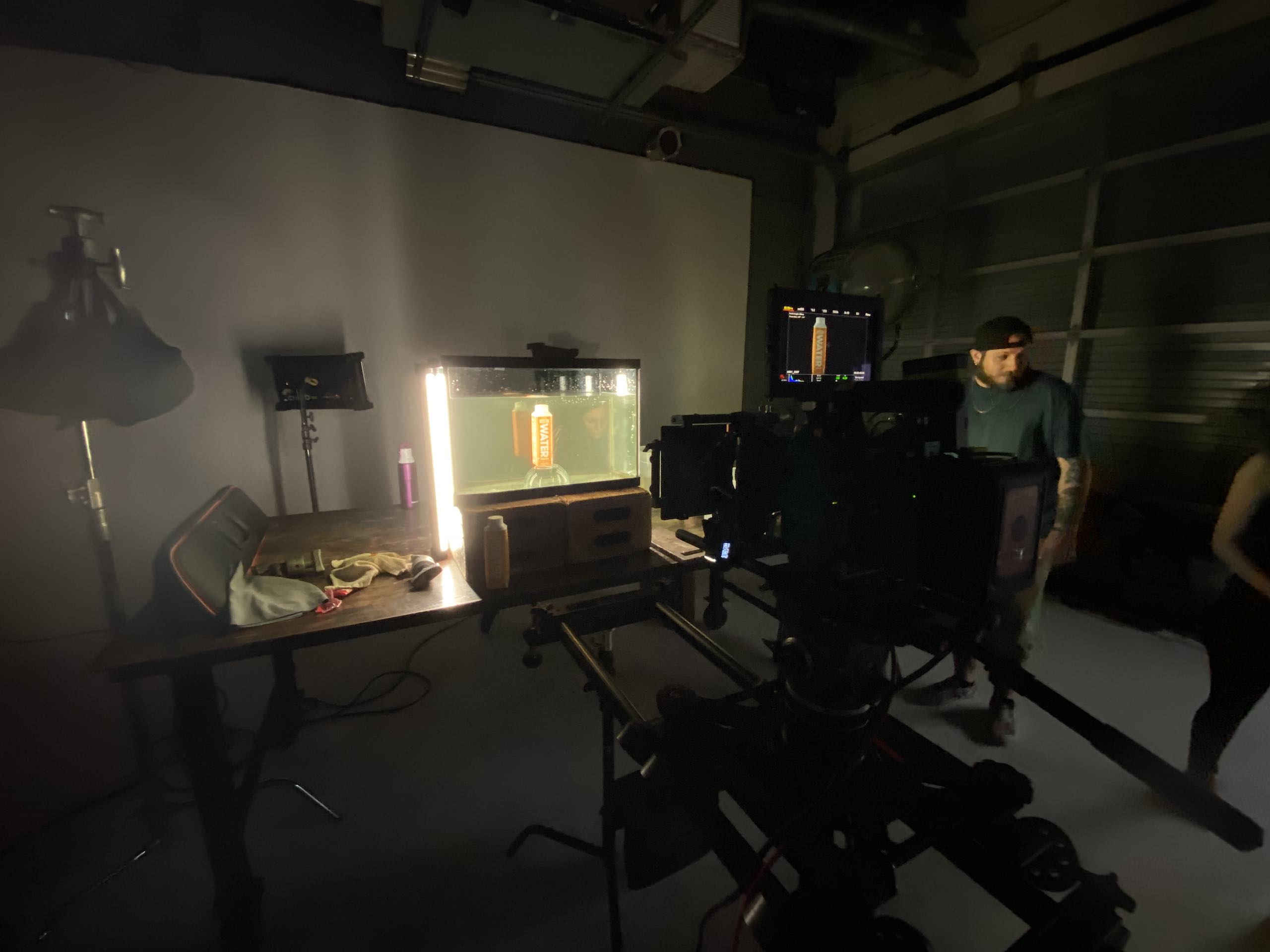 Video camera trained on an orange drink carton in a tank filled with water in a studio