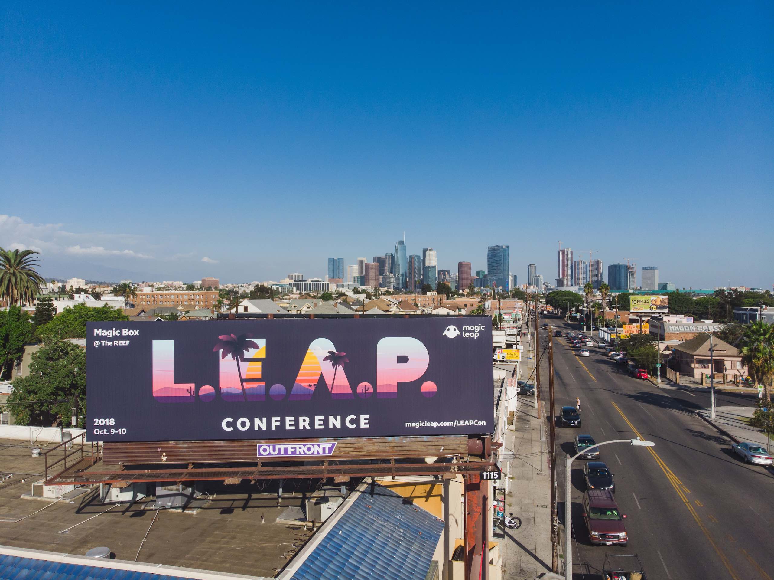 DUPLICATE View from drone of LEAP Conference billboard on display near road with cars parked and driving by