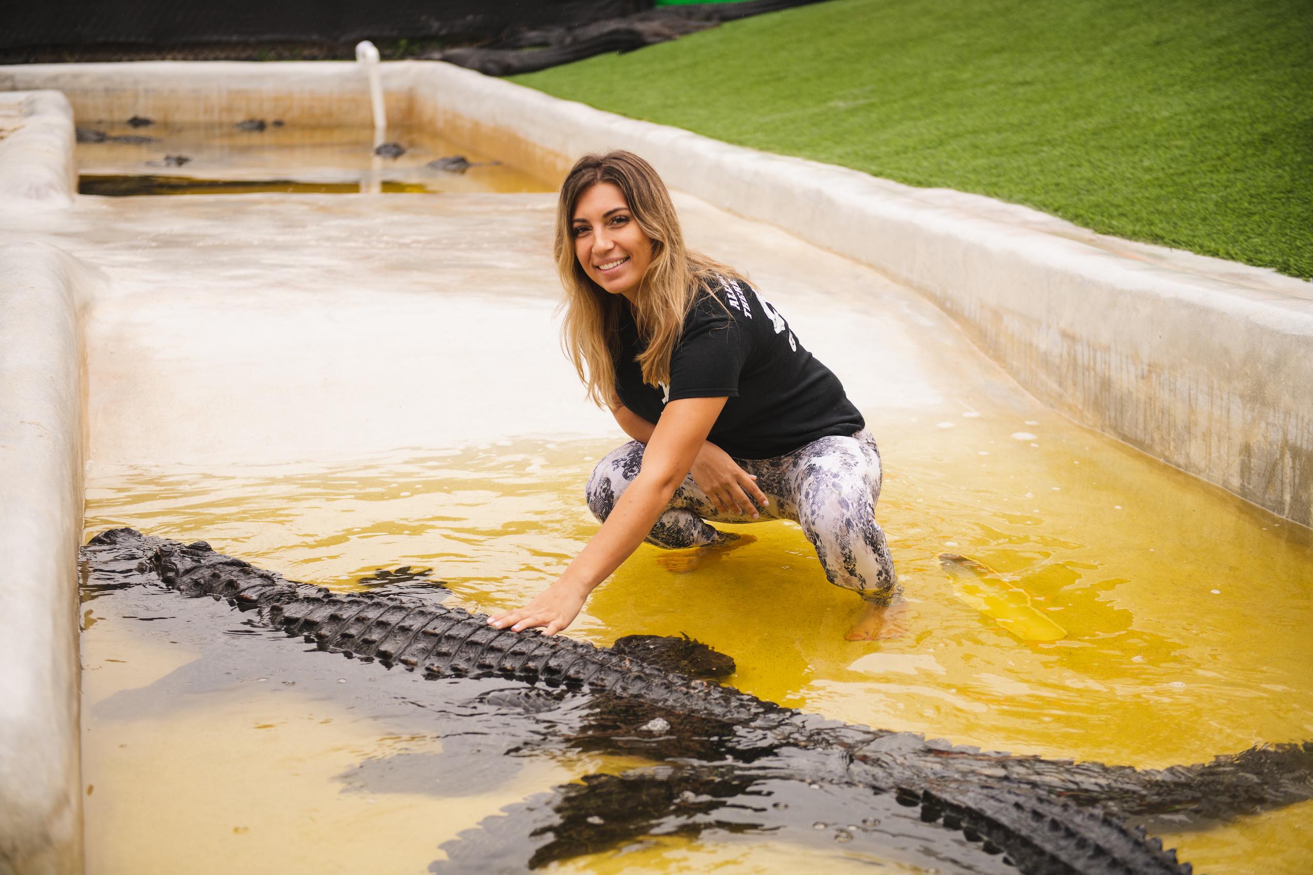 Everglades Holiday Park Woman with long blond hair posing with an alligator in water