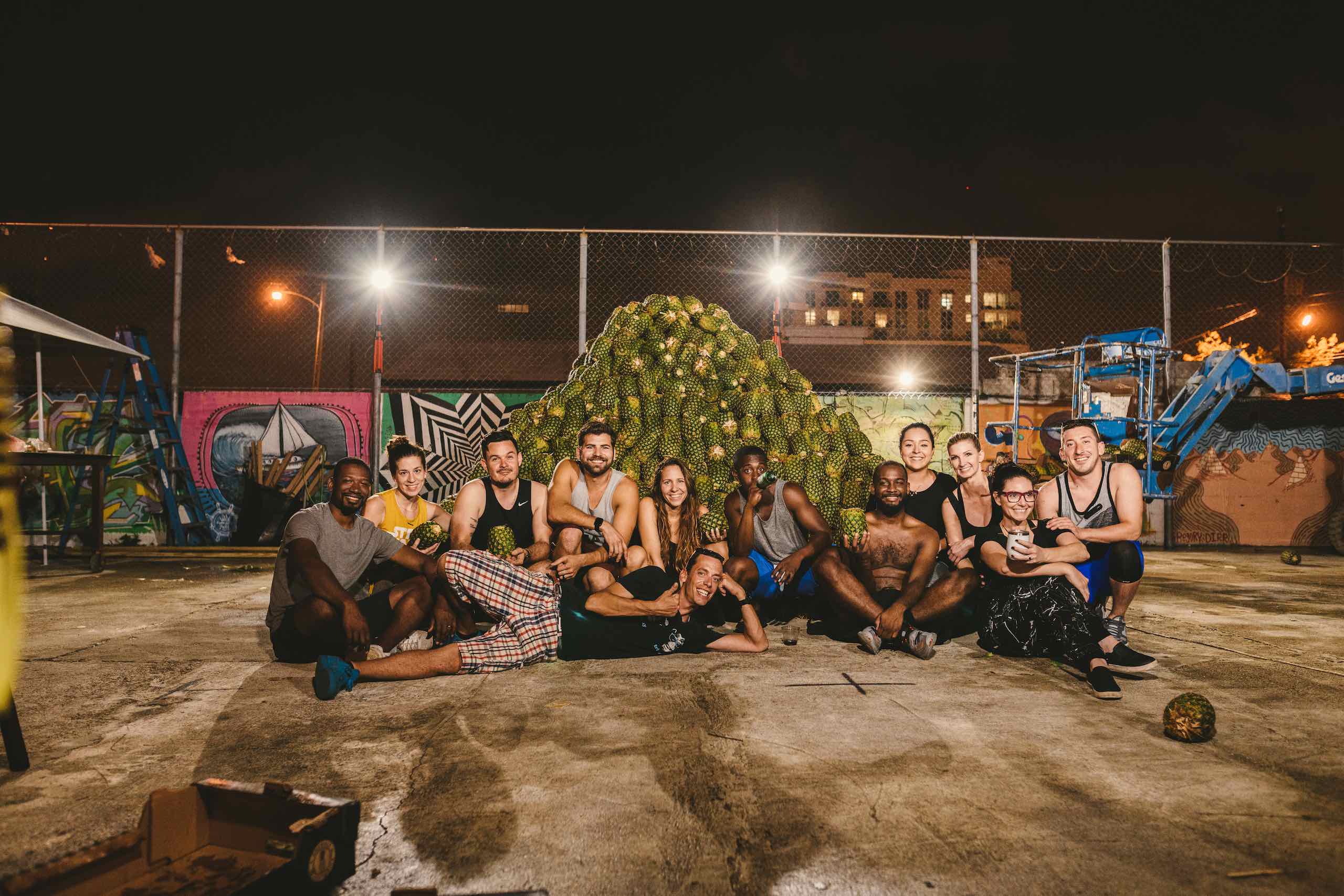 Artwalk 2018 May Pineapple Pyramid display with many men and women posing in front of it at night