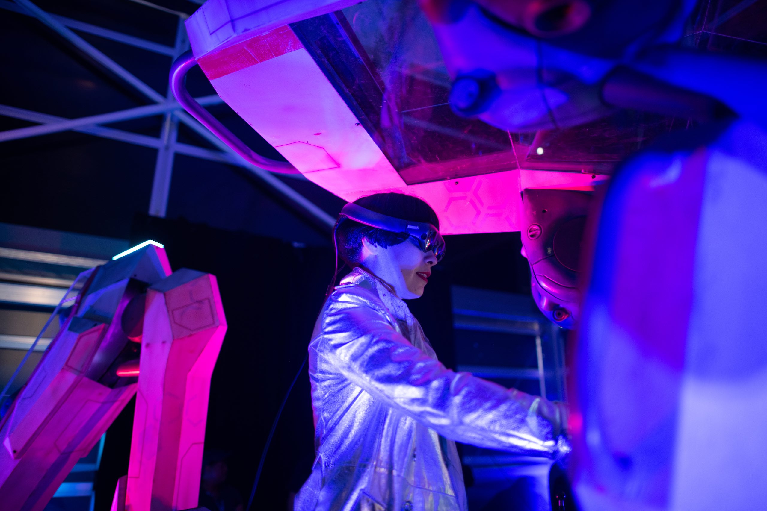 Side profile of woman using a console wearing Lightwear equipment in a bluish and reddish lights