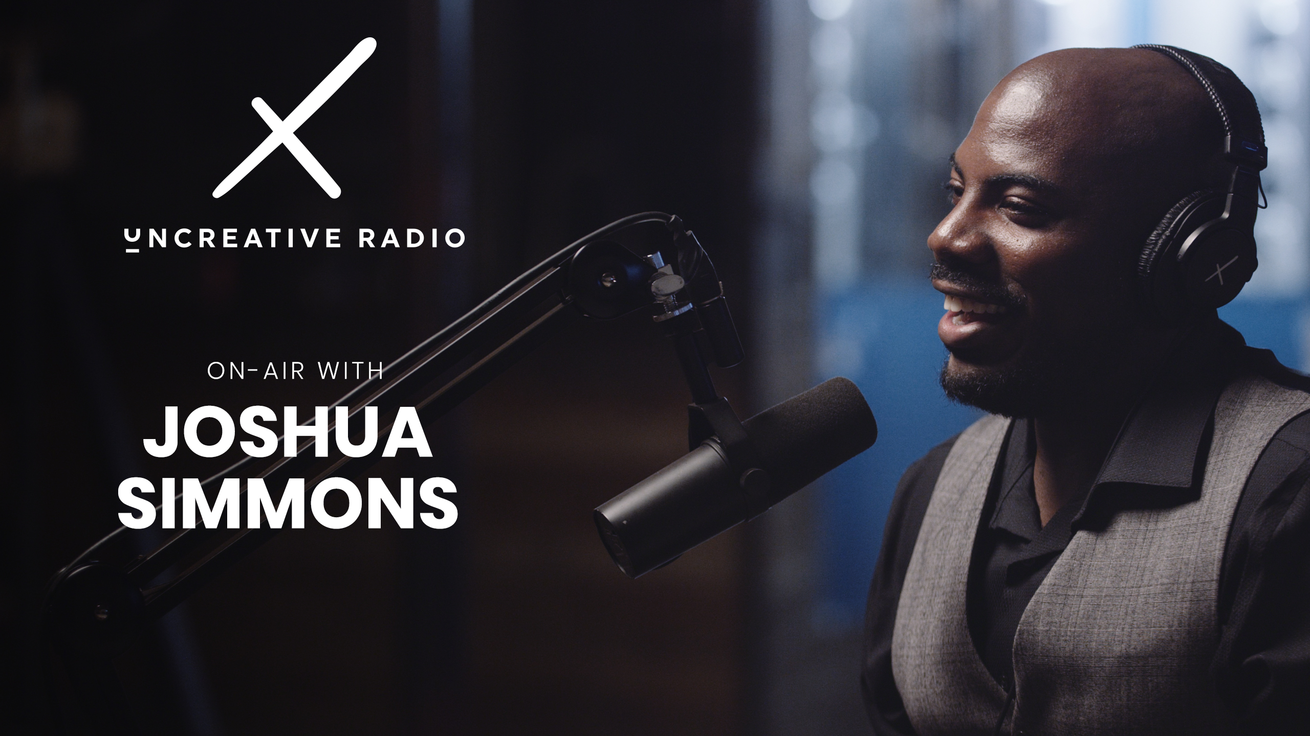 Uncreative Radio On Air with Joshua Simmons wearing black headphones smiling and by microphone