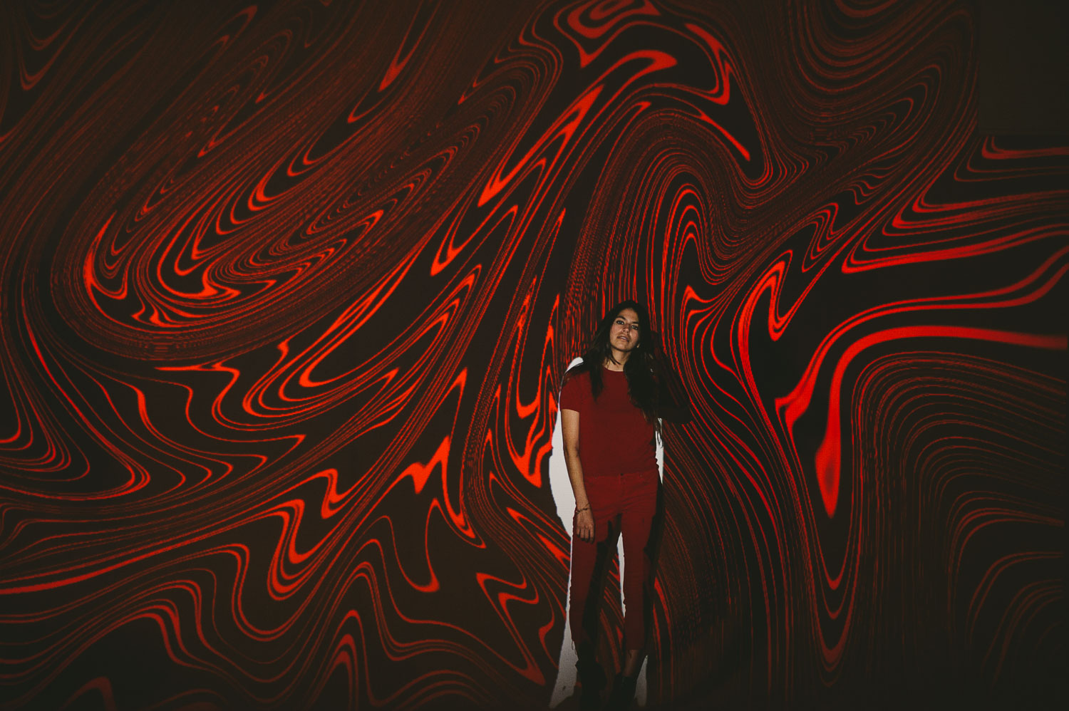 Artwalk self projection live art exhibit by C&I Studios with woman with long black hair in front of red artwork
