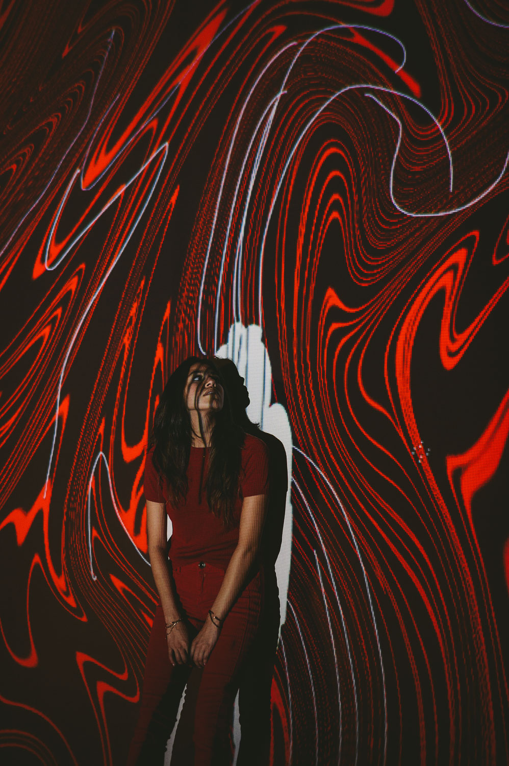 IU C&I Studios Post Artwalk self projection live art exhibit by C&I Studios with woman with long black hair in front of red artwork looking up