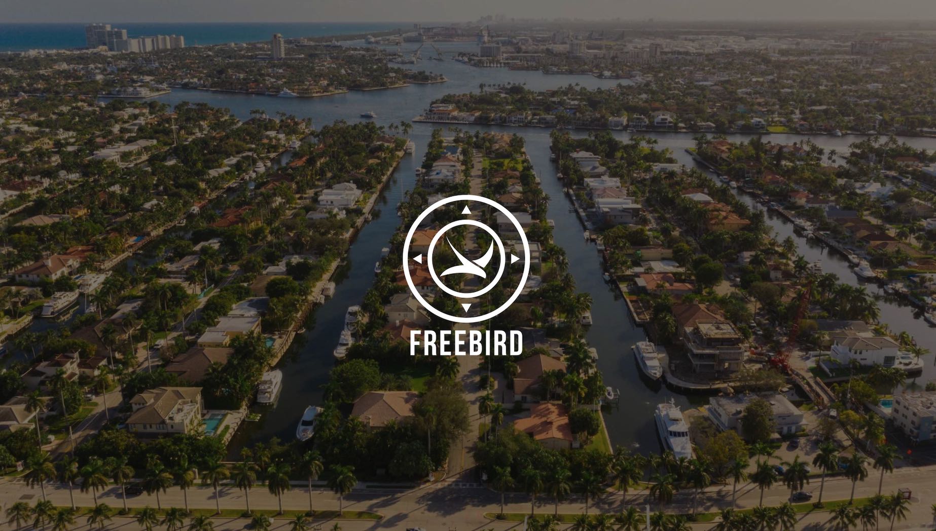 White Freebird logo website development on dimmed background aerial view of houses with canals with boats anchored
