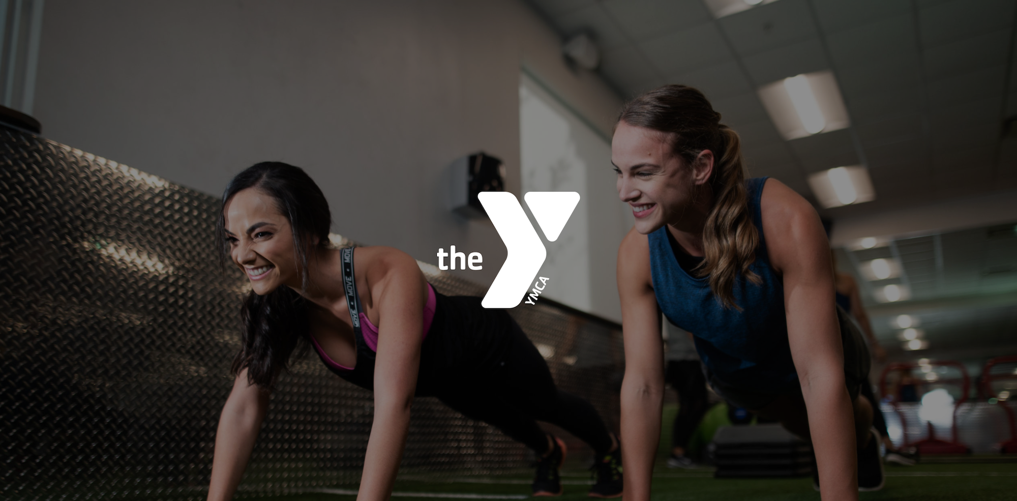 Two young women with long hair doing pushups at the YMCA.