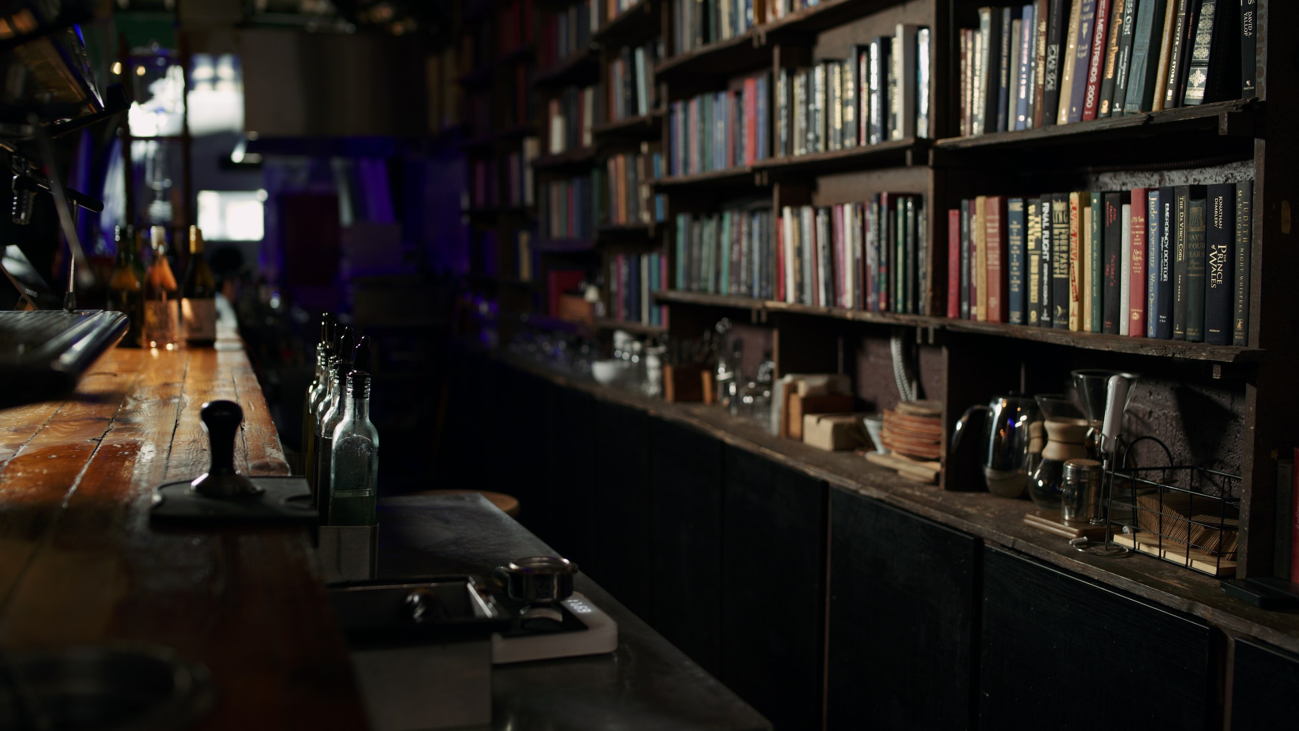 Side profile of a bar with alcohol bottles and books on bookshelves