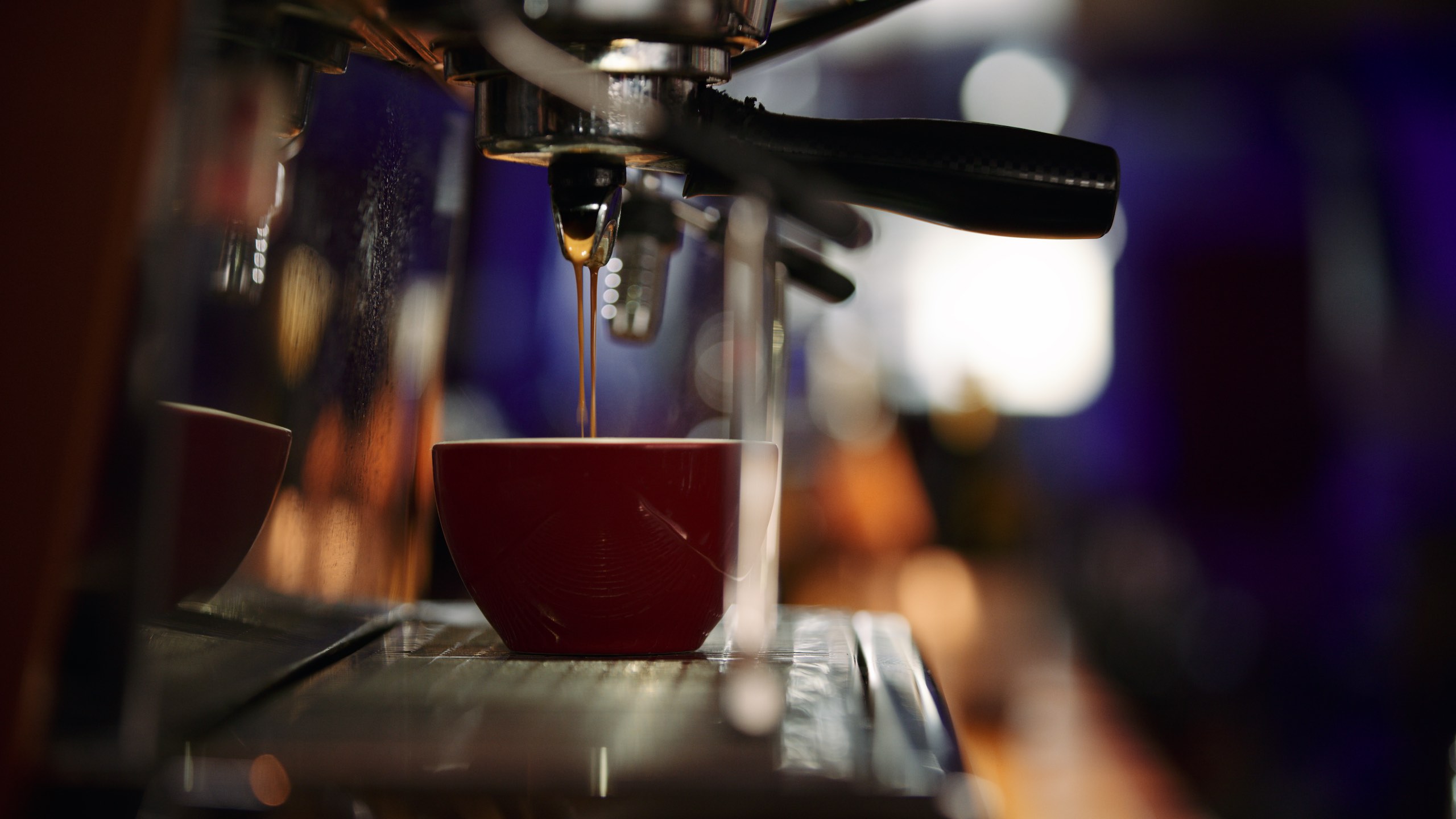 Side profile of coffee pouring in a red cup