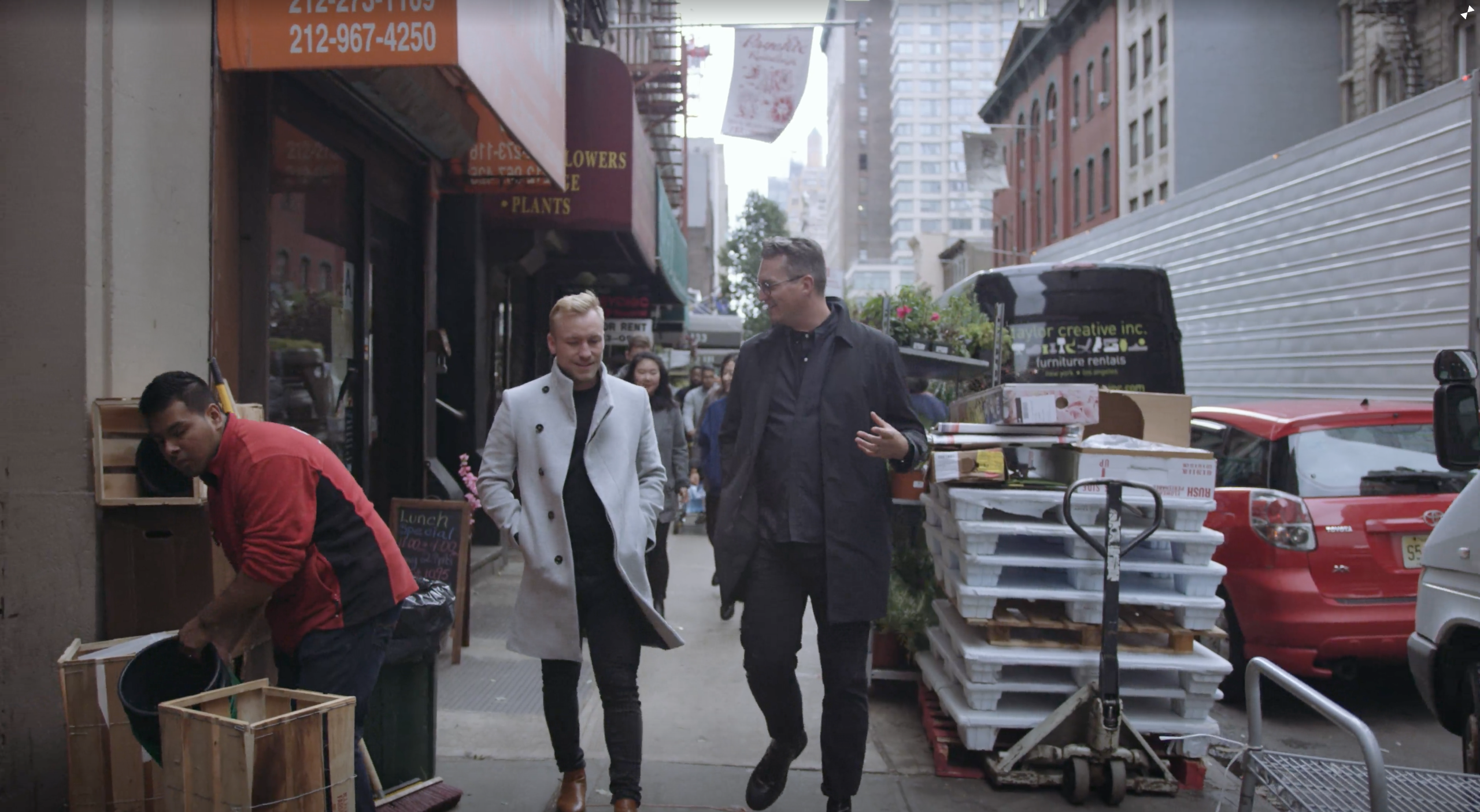 EDSA Design Studio NYC with two men walking down a street talking with cars parked nearby
