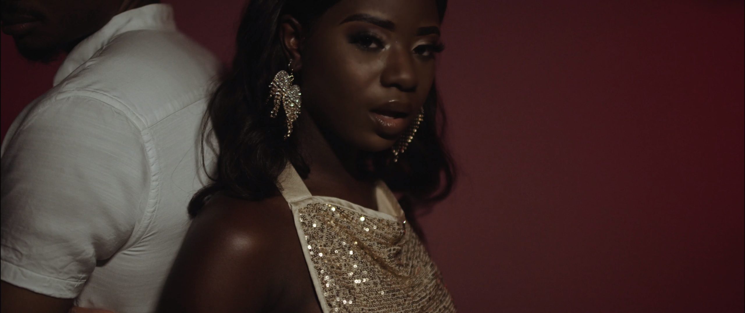 Laudz Fedeles Moody Music Video with headshot of her wearing a glittery dress back to back with a man wearing a white Polo shirt