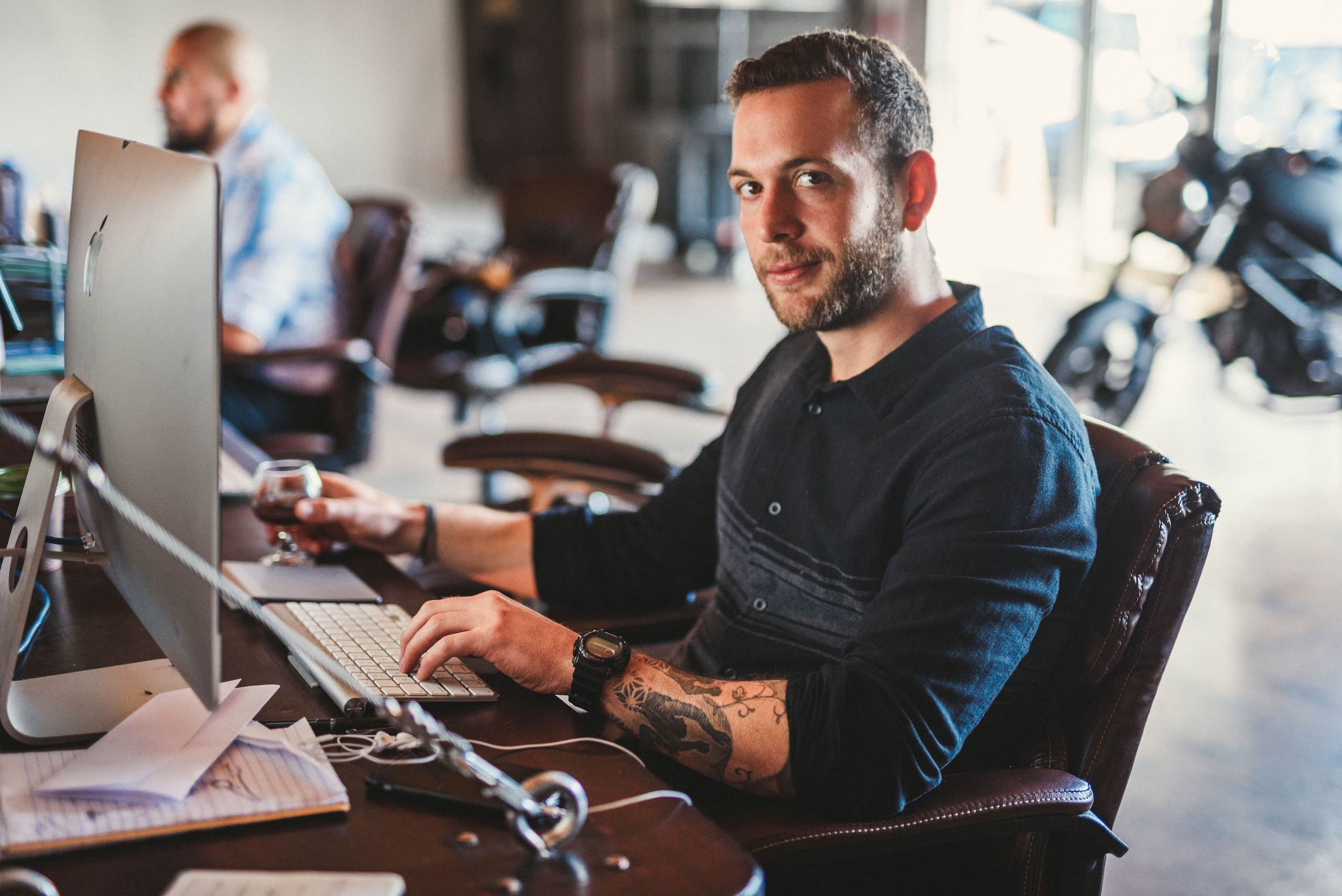 SEO Copywriting C&I Candid side profile of a tattooed crew member posing for the camera by desktop computer in an office