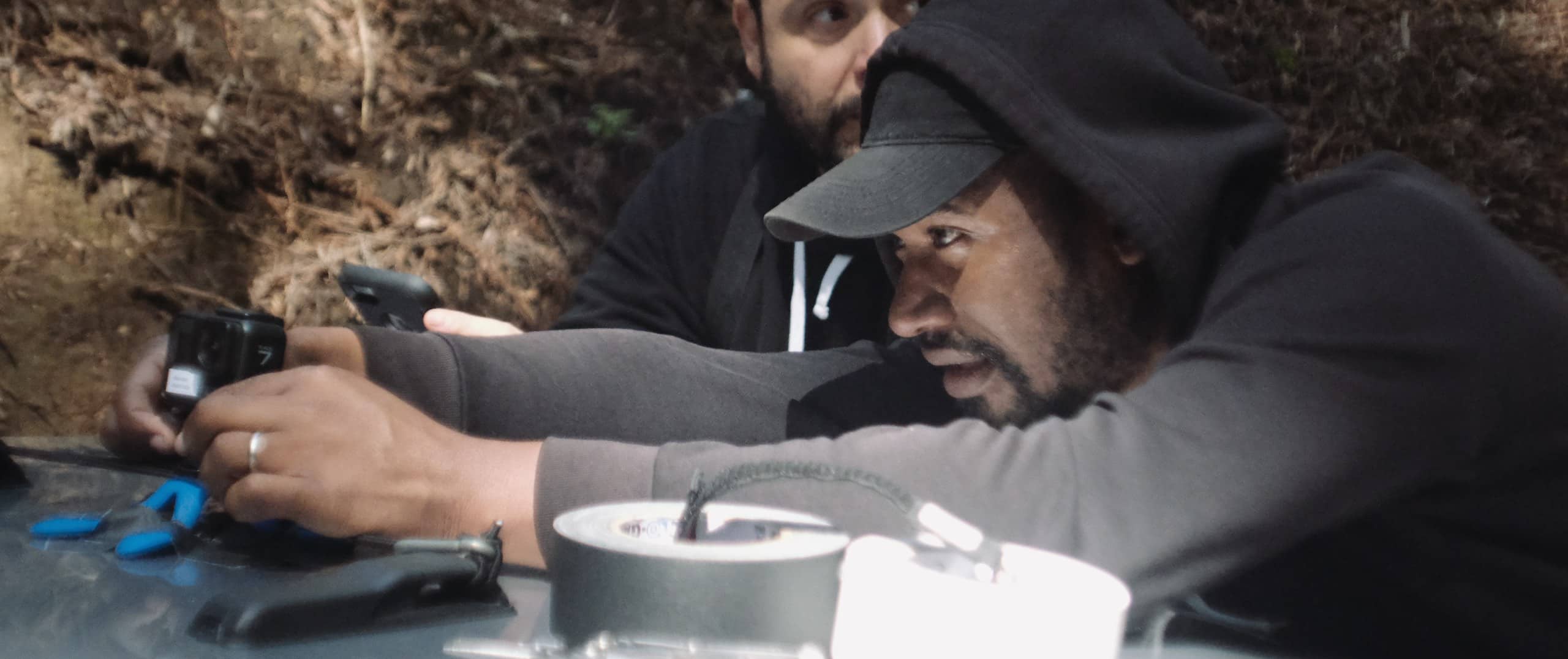 Agency Secret What Makes Killer Product Photography with Joshua Miller wearing black cap and sweatshirt using camera with another crew member nearby