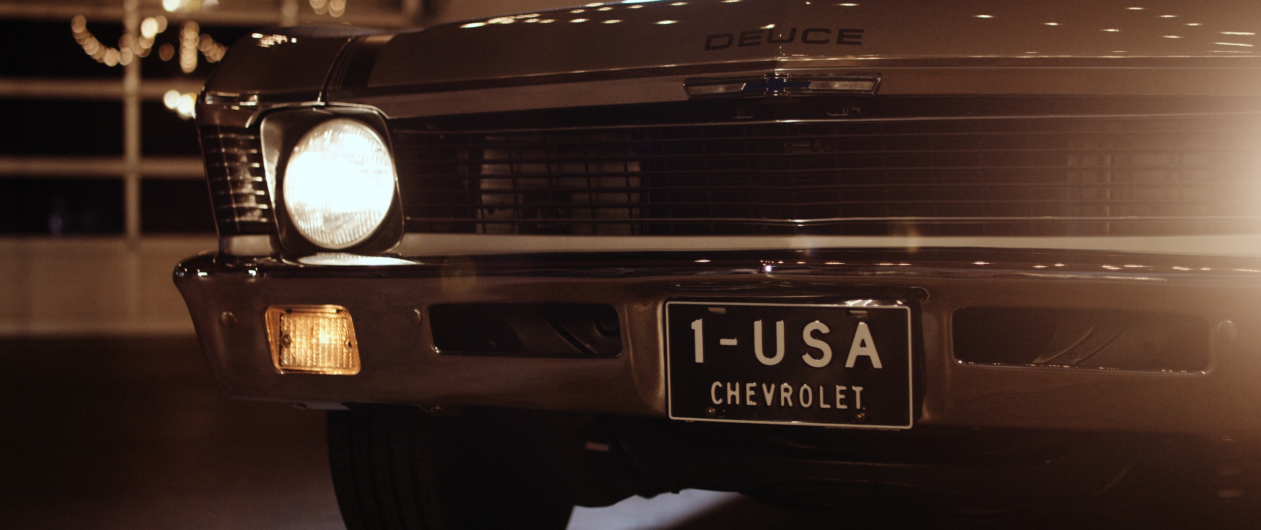 The Dailies Episode 202 BTS Footage with closeup view of a vintage Chevrolet car with headlights on