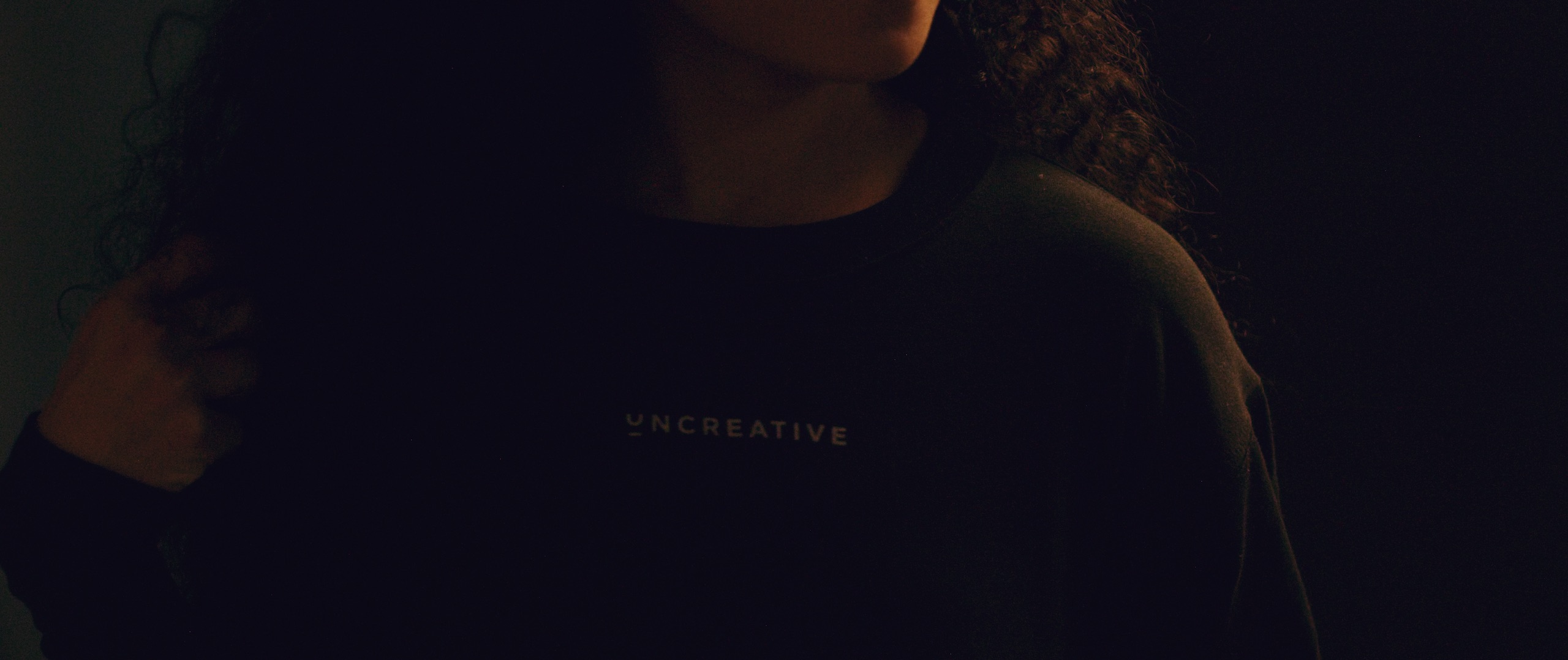 The Dailies Episode 4 The Making of Uncreative Merchandise Shop Closeup of woman wearing black Uncreative sweatshirt
