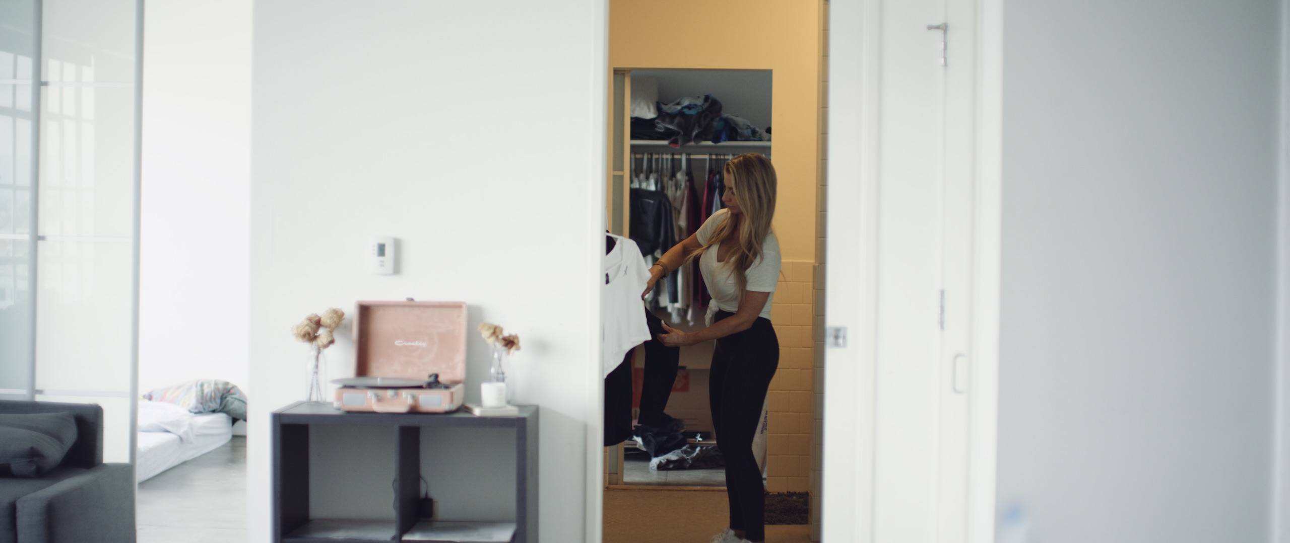 The Dailies Episode 4 The Making of Uncreative Merchandise Shop Side profile of woman with long blond hair working with Uncreative crop top in walk in closet