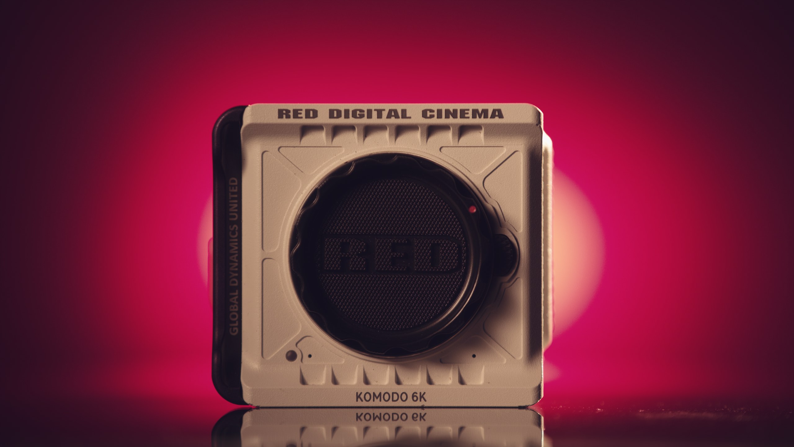 RED Komodo Distance Test White colored RED-Komodo-Compact-Cinema-Camera against a red backdrop