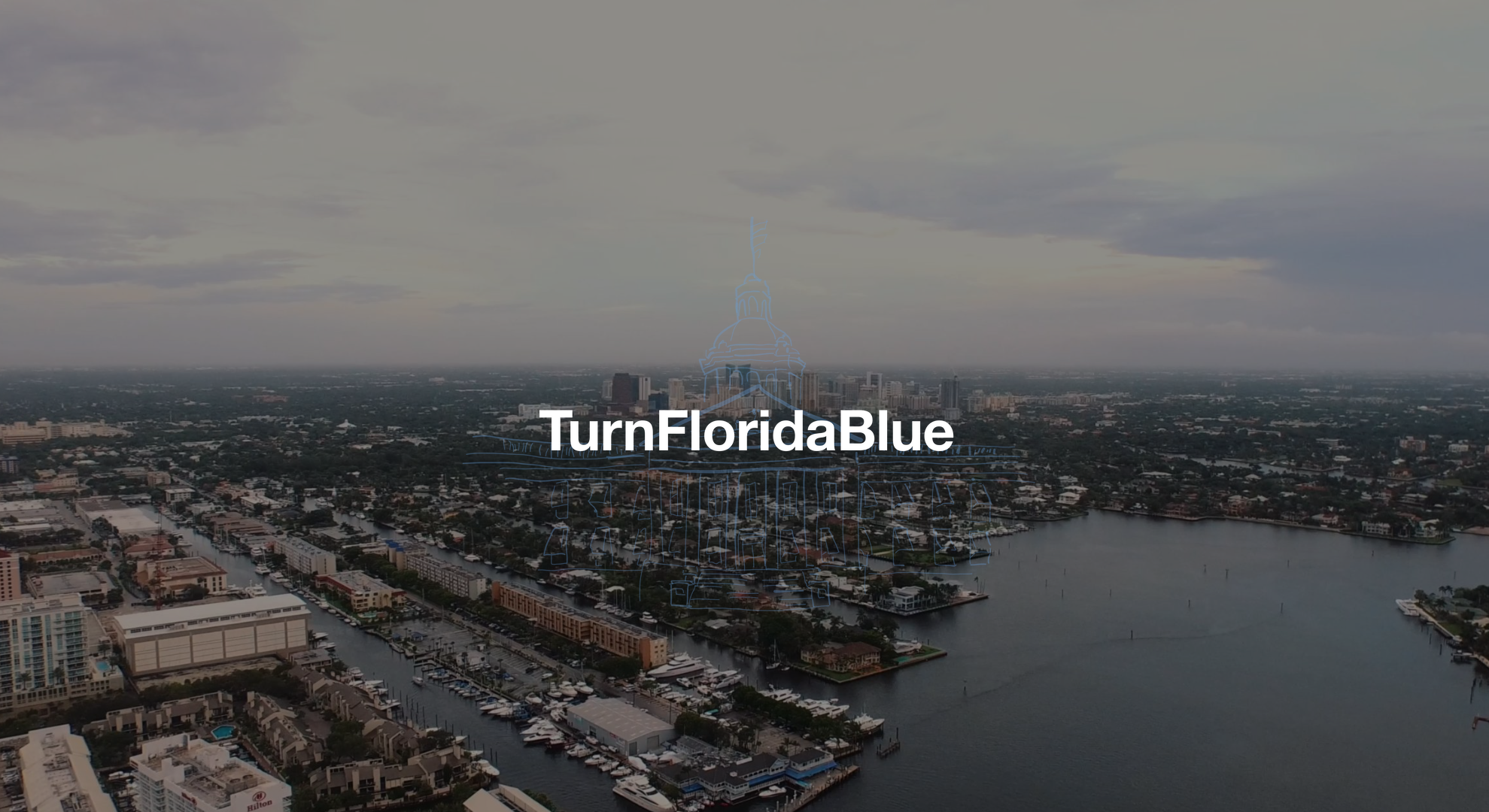 Florida House Victory Cindy Polo White Turn Florida Blue text on a backdrop aerial view of ports with boats