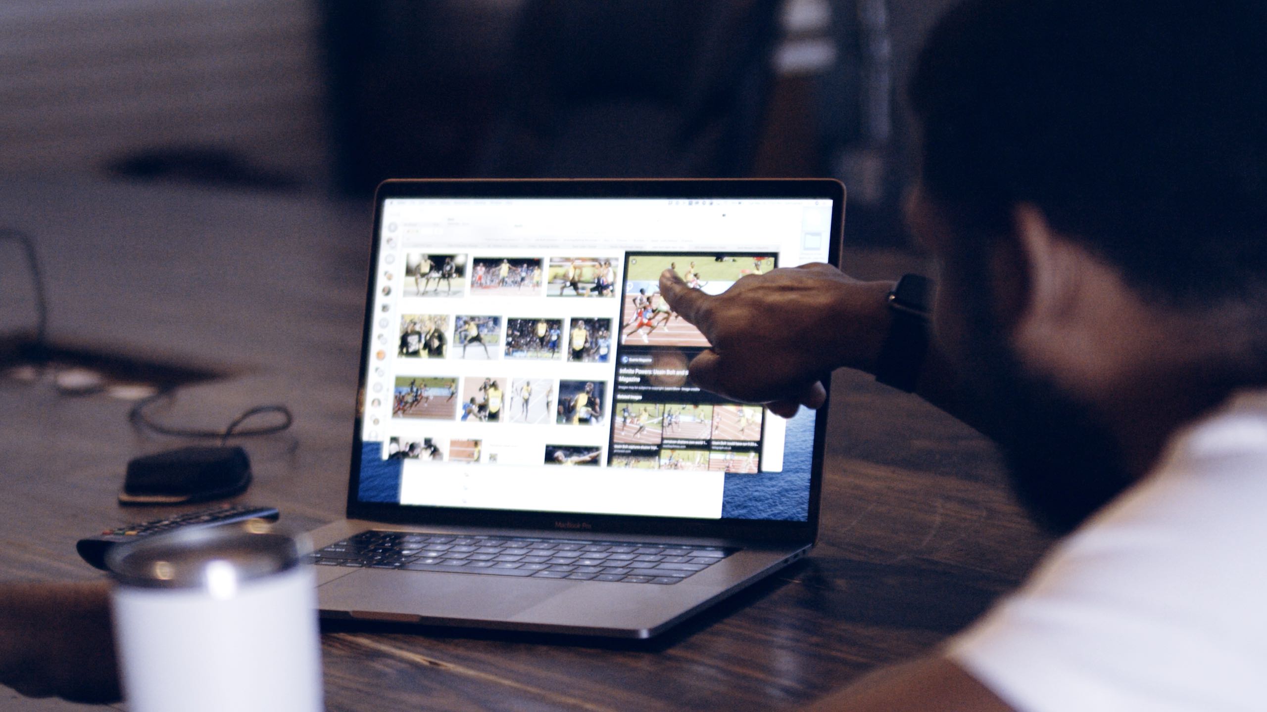 Social Media View from behind of man pointing at something on laptop monitor