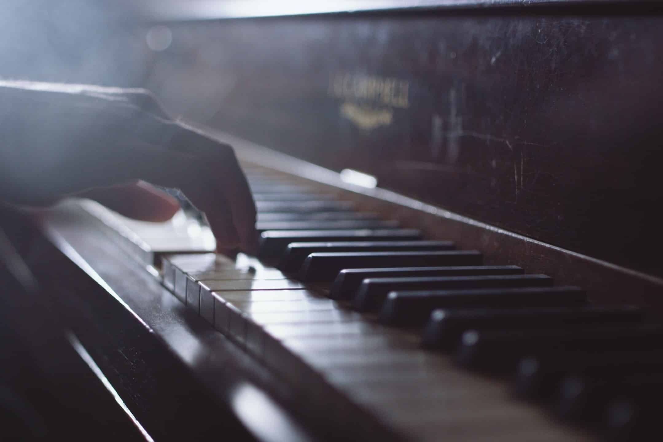 Piano with closeup of hand playing piano