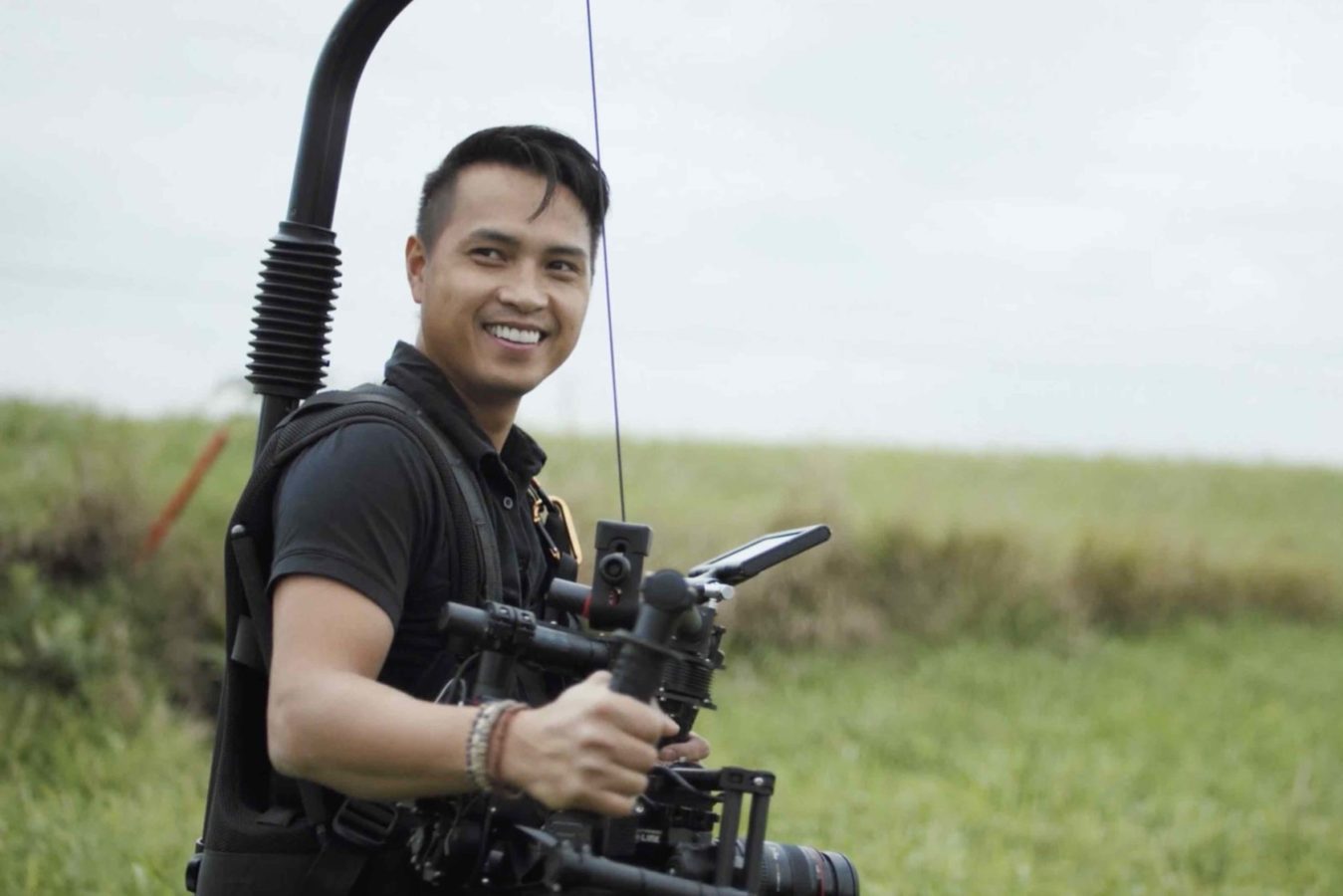 Production Resources Hire Crew Tom Van side profile using video equipment in a field smiling for the camera