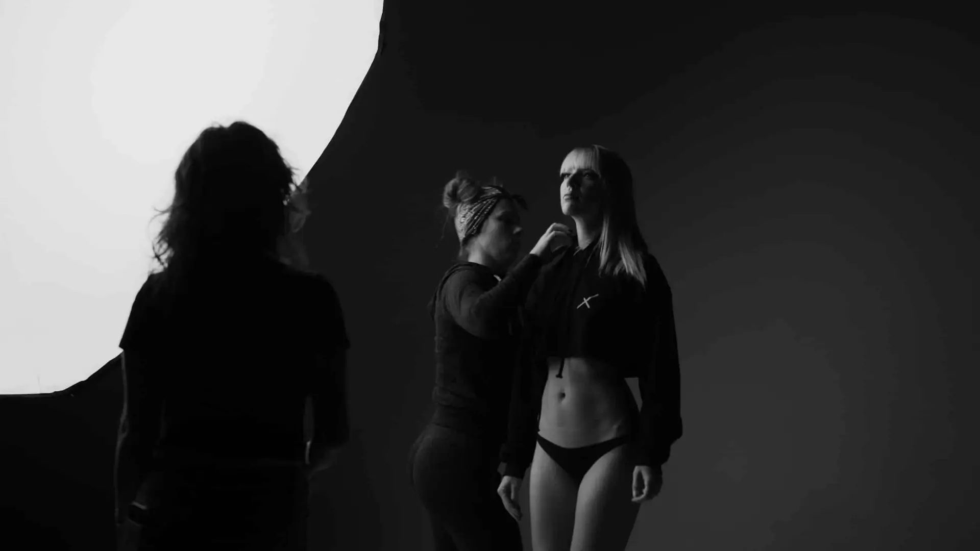 We Are Who We Are 2 Black and white of makeup artist working on model AJ Knapp while another crew member looks on