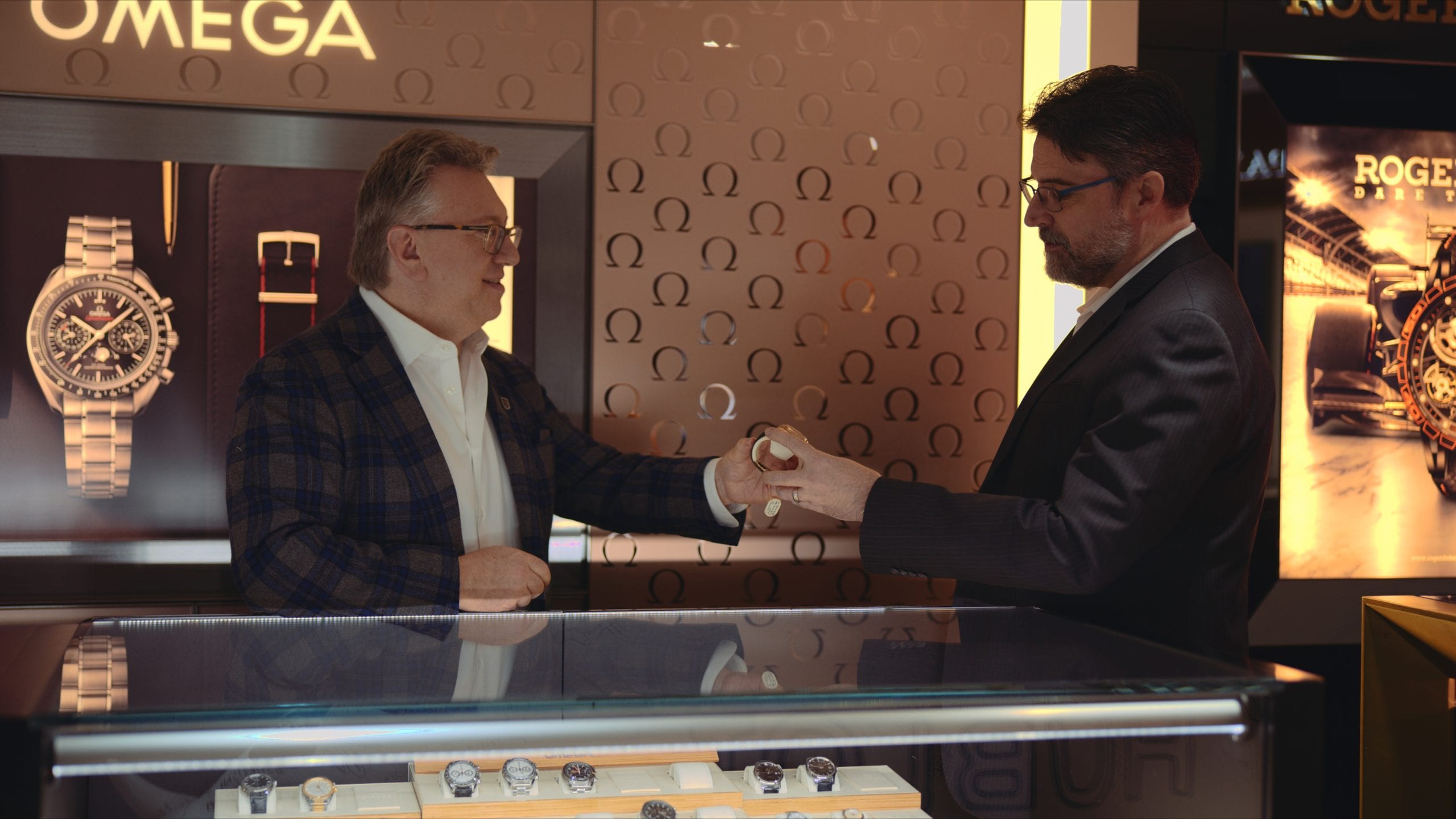 Geneva Seal Chicago Jeweler handing a watch to another man in a jewelry shop