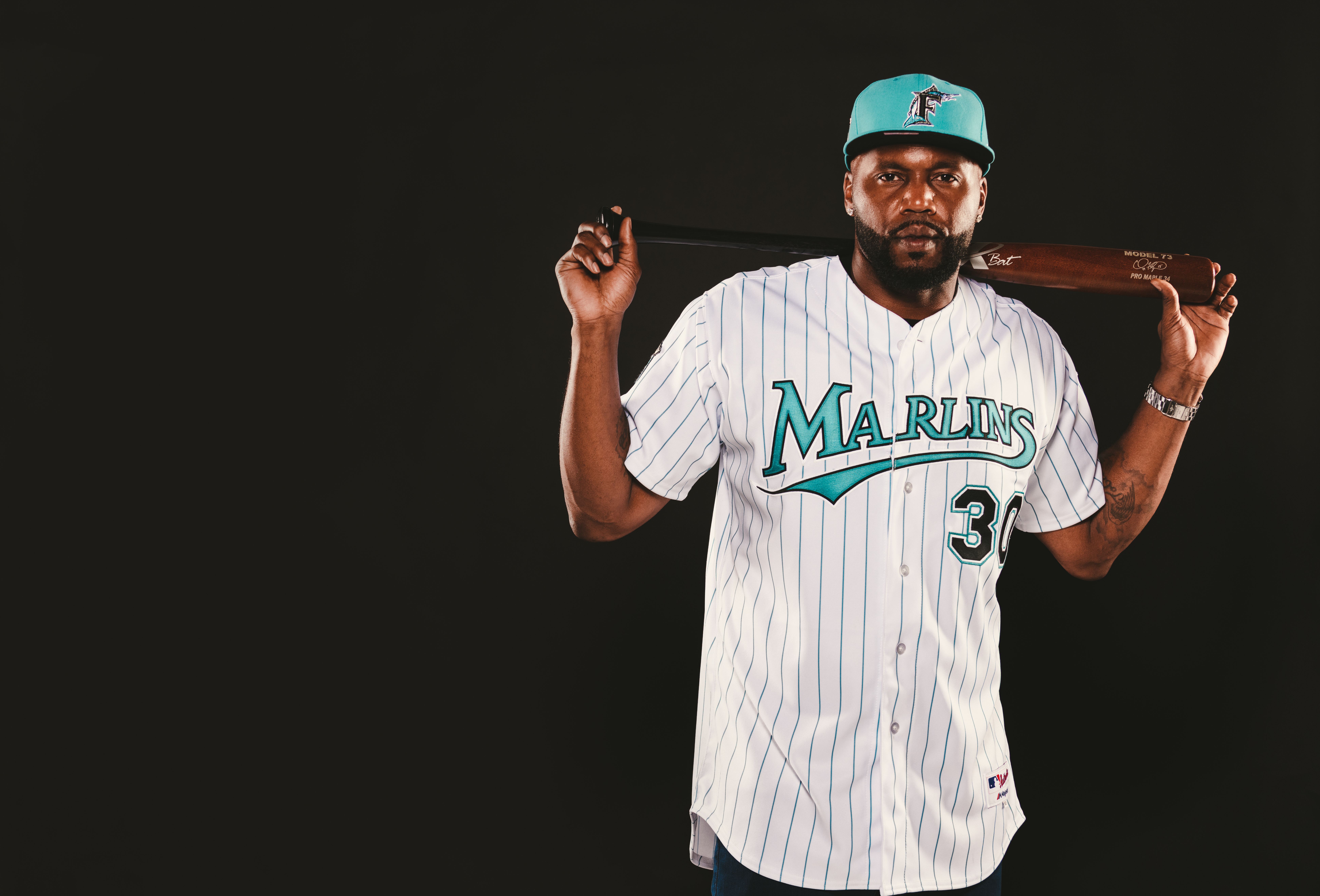 IU C&I Studios Ball Cap Liner Marlins baseball player wearing a cap posing for the camera with a bat across his shoulders