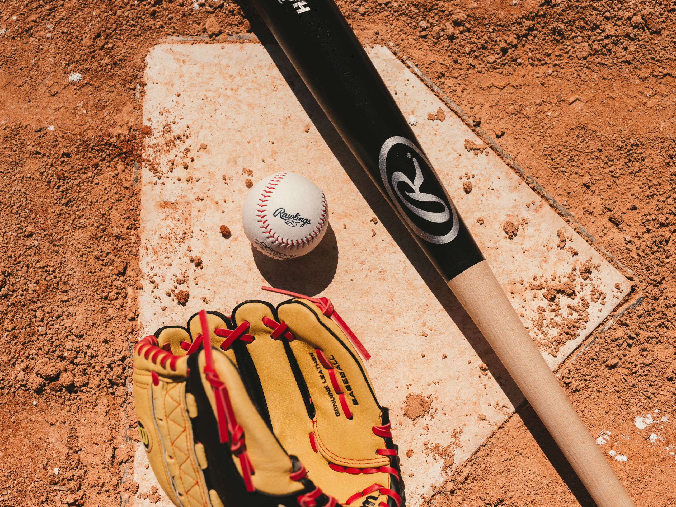 IU C&I Studios Ball Cap Liner Closeup of a baseball bat, mitt, and baseball on a home base on a baseball field
