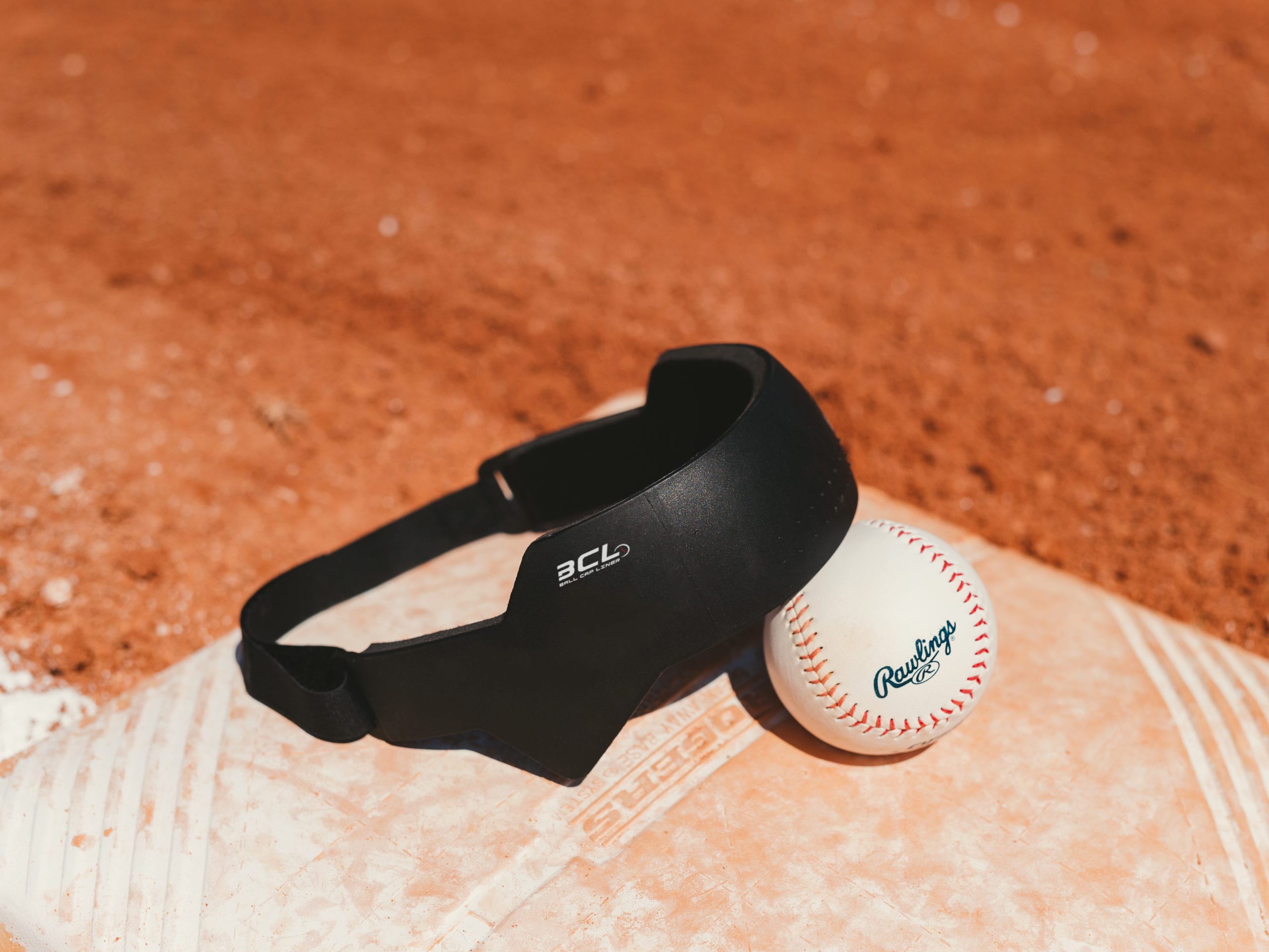 IU C&I Studios Ball Cap Liner Closeup of BCL and baseball on a baseball base on a baseball field