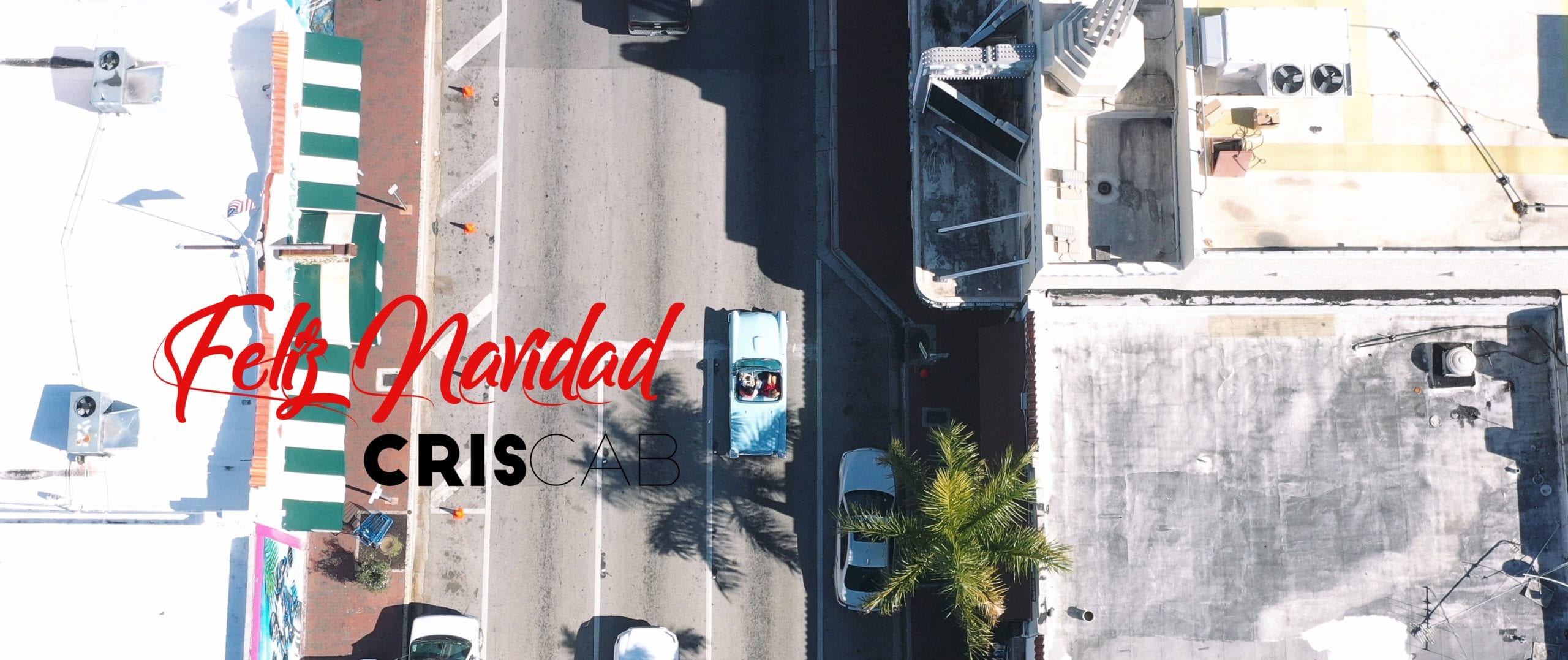 Feliz Navidad Cris Cab title card with aerial view of town in background