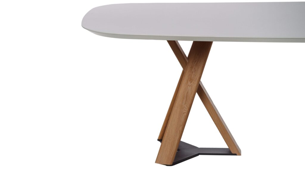 Closeup of part of white oval table with brown legs on display