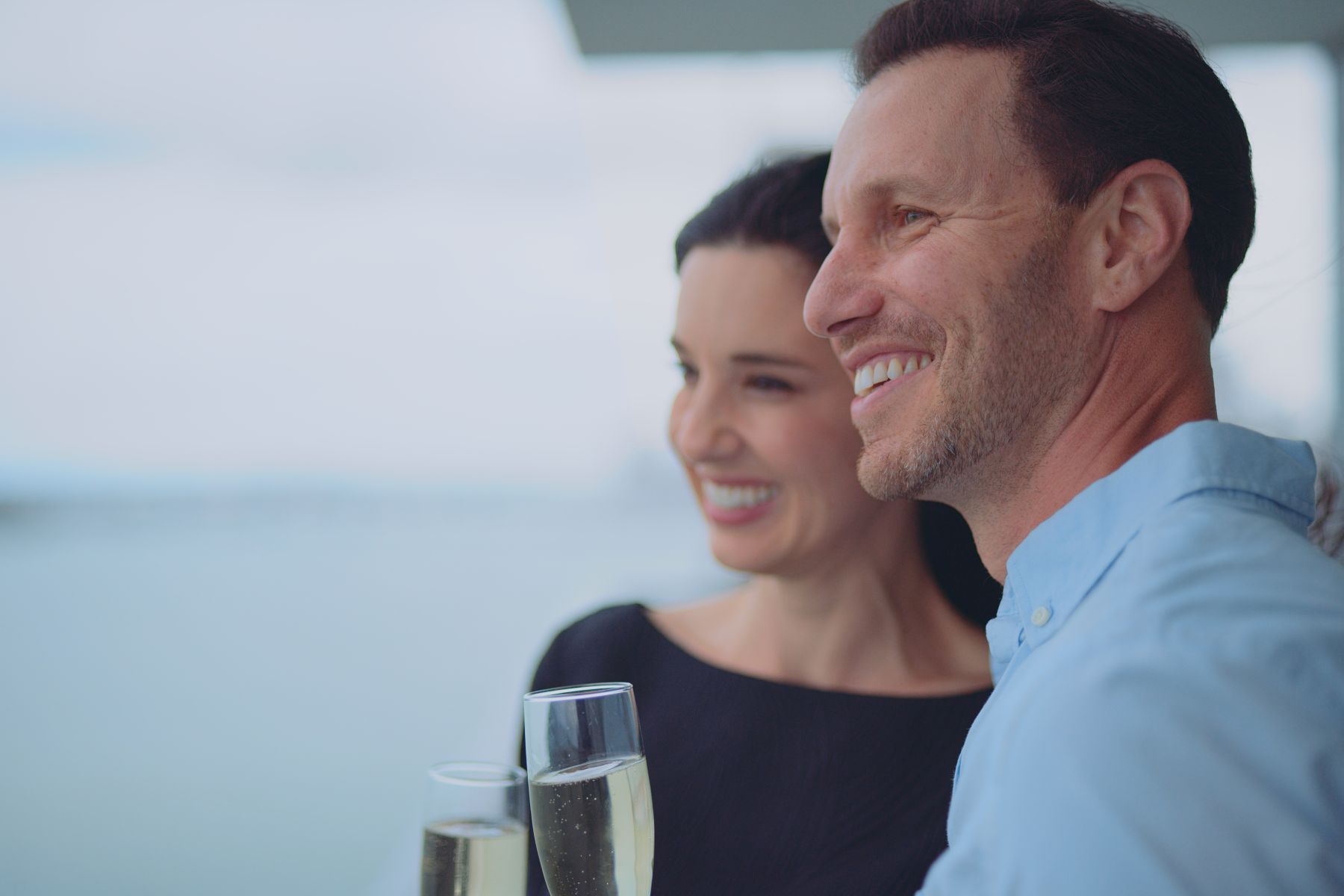 IU C&I Studios Portfolio Macken Koya Bay Side profile of man and woman smiling looking out over the water holding drinks