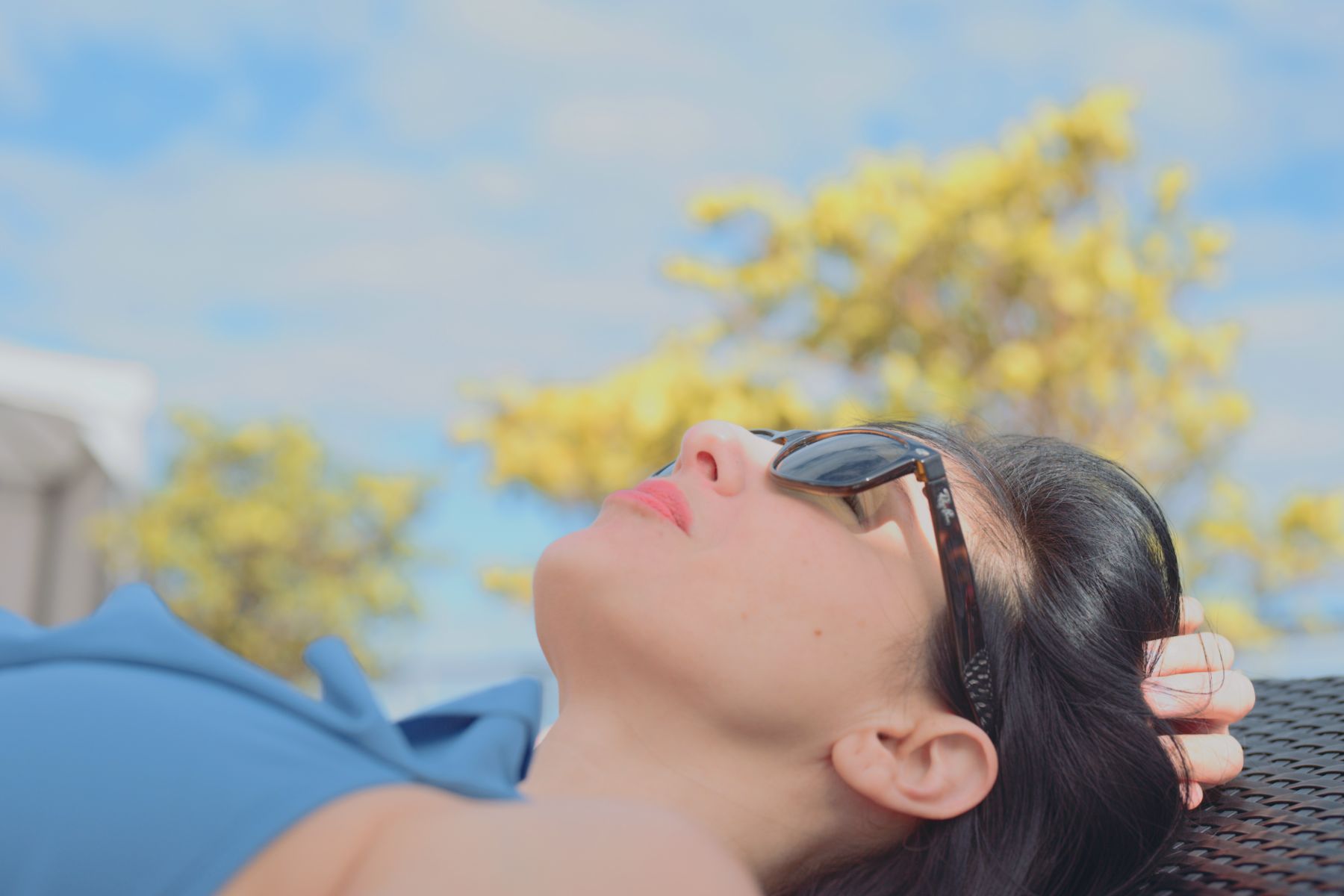IU C&I Studios Portfolio Macken Koya Bay Side profile of woman wearing a light blue bathing suit and sunglasses lying down sunbathing