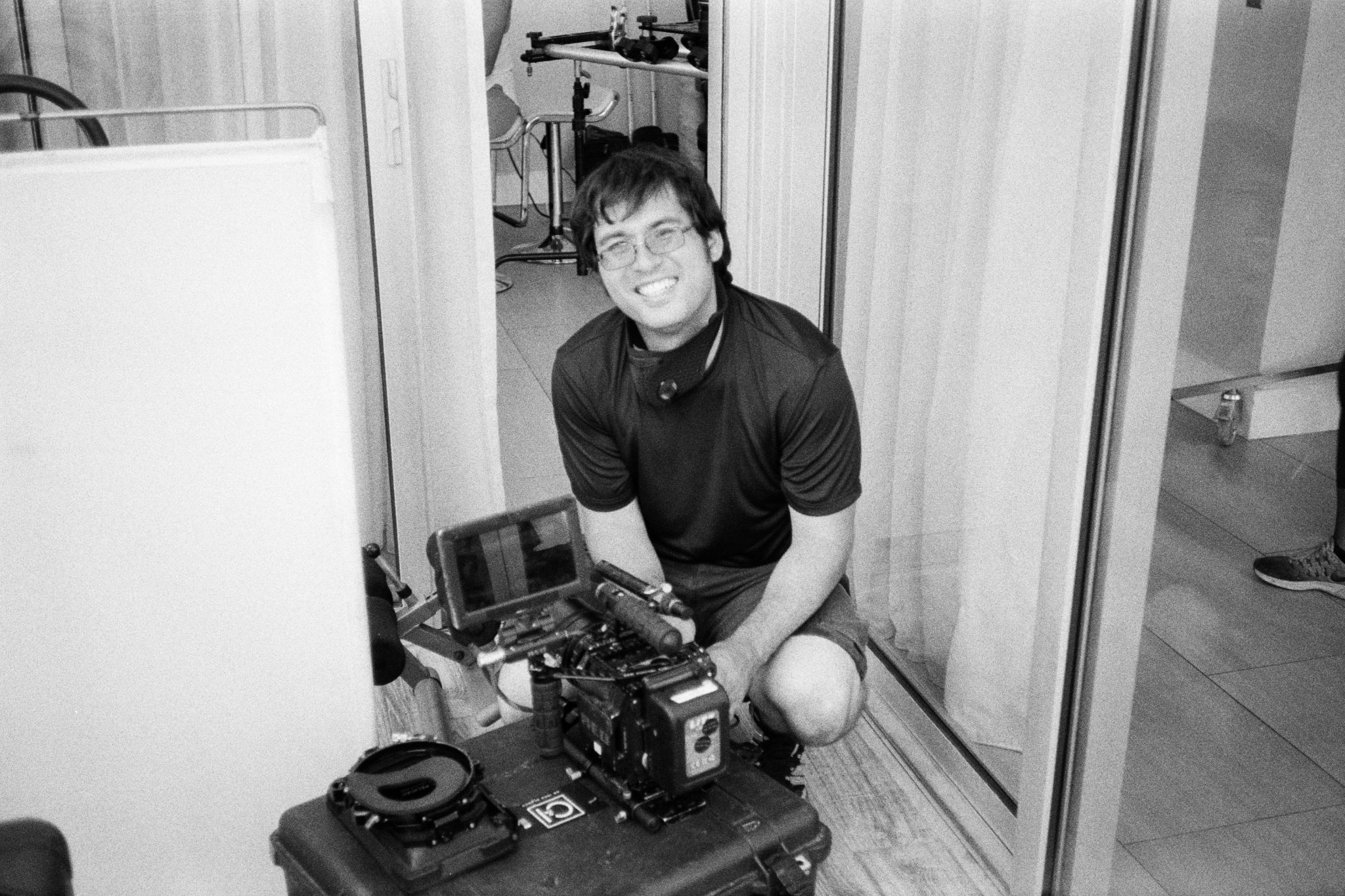 Black and white of Chris Kennedy posing with camera crouching down